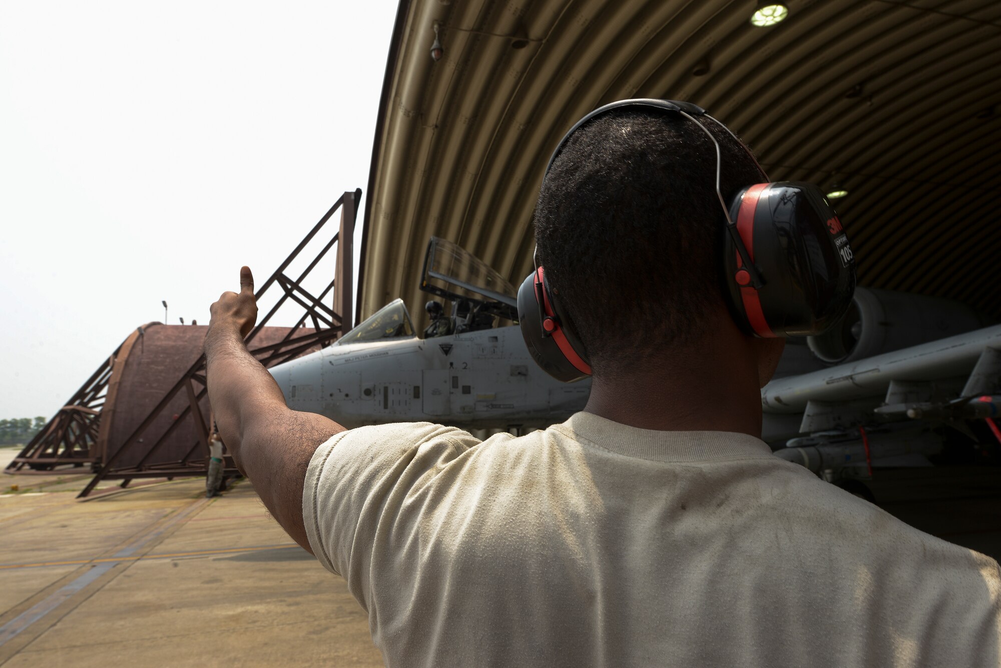 An Airman from the 25th Aircraft Maintenance Unit weapons load crew section signals a thumbs up on the wing check while an A-10 taxis June 23, 2015, at Osan Air Base, Republic of Korea. The weapons section does the wing checks to ensure the plane's extremities have a clear path to leave the bay. (U.S. Air Force photo by Staff Sgt. Jake Barreiro/Released)