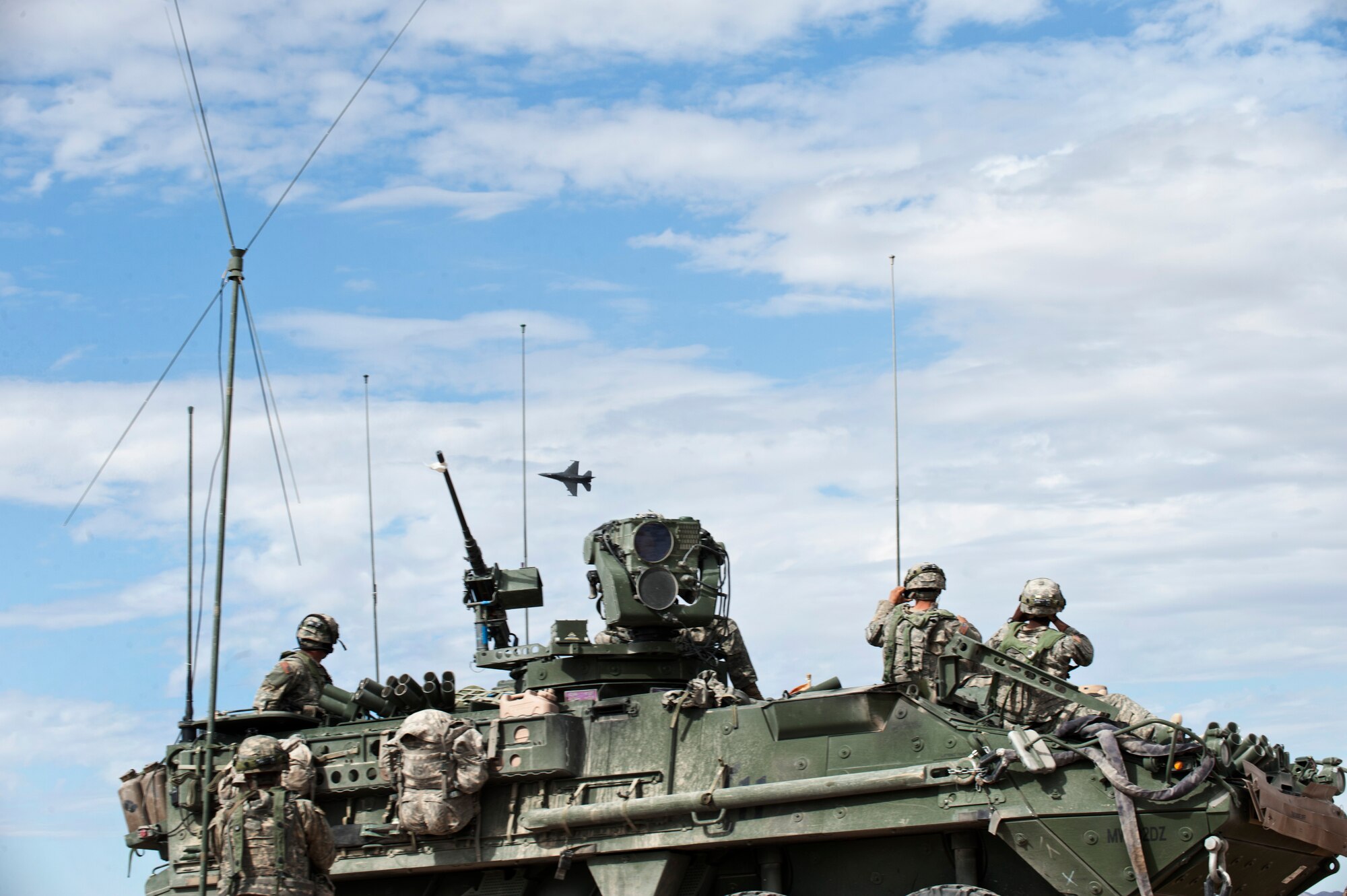 Soldiers from the 1st Armored Division, 1st Stryker Brigade Combat Team, Fort Bliss, Texas, look on as an F-16 Fighting Falcon executes a “show of force” in the skies over the National Training Center Range, Fort Irwin, Calif., during a Green Flag 15-08 training scenario June 12, 2015. In many situations, an aircraft executing a low pass over a conflict zone can act as a deterrent to potential enemy combatants. (U.S. Air Force photo by Senior Airman Joshua Kleinholz)