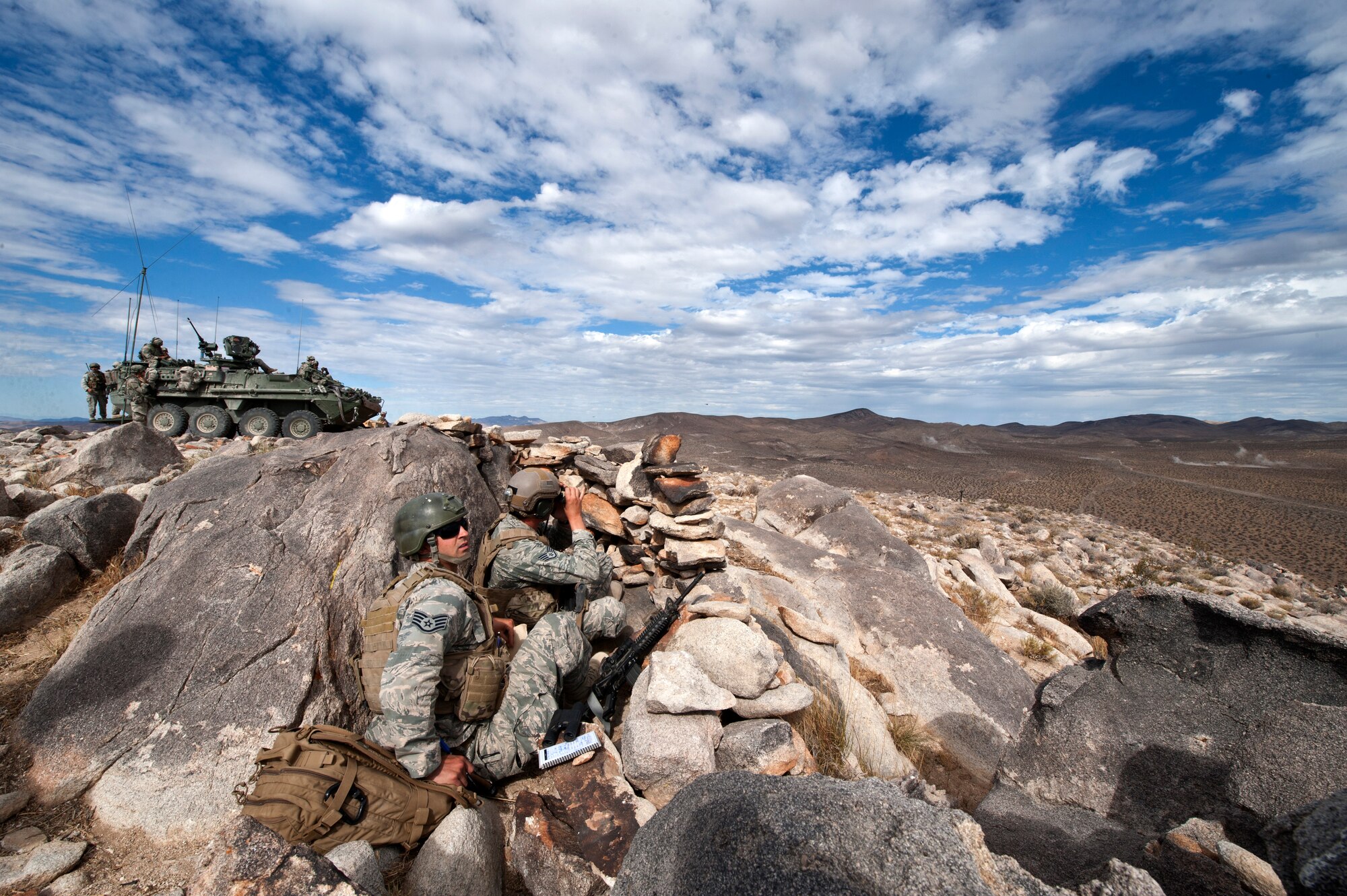 Tactical air control party members from the 7th Air Support Operations Squadron, Fort Bliss, Texas, monitor radios from a defensive fighting position while AH-64D Apache helicopters from the 1st Battalion, 227th Aviation Regiment, Fort Hood, Texas, fire upon a group of enemy vehicles in the distance during a Green Flag 15-08 training scenario at the National Training Center, Fort Irwin, Calif., June 12, 2015. The Apaches were just one phase of a joint integrated attack maneuver that combined simultaneous fire from artillery, armored vehicles, and both rotary and fixed wing aircraft. (U.S. Air Force photo by Senior Airman Joshua Kleinholz)
