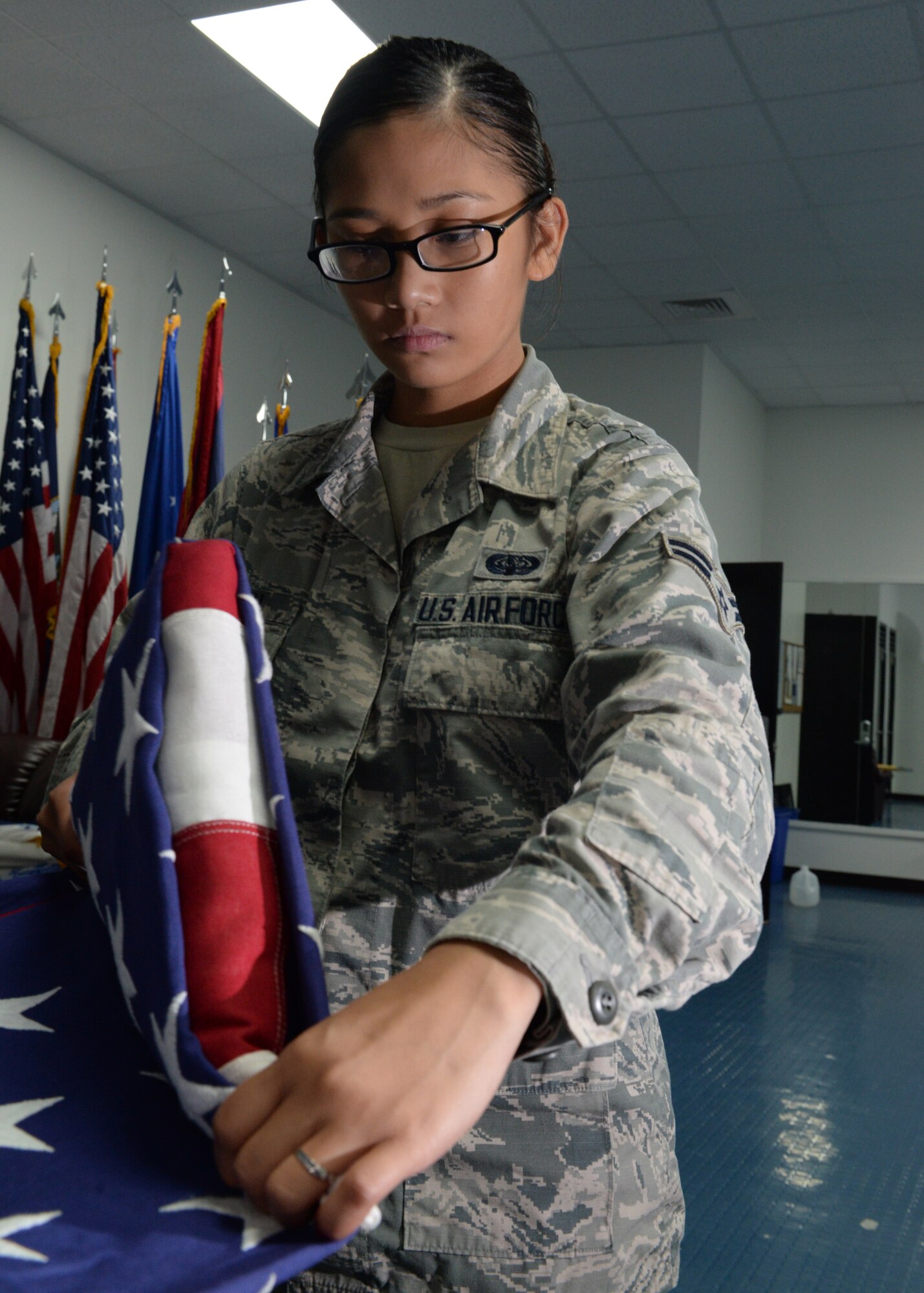 Airman 1st Class Vanessa Vann, a ceremonial guardsman from the 36th Communications Squadron, performs a two-man flag fold during Andersen Blue Knights Honor Guard weekly training June 24, 2015, at Andersen Air Force Base, Guam. Honor guard members follow strict guidelines while performing their duties to provide traditional military honors at ceremonies and funerals. (U.S. Air Force photo by Senior Airman Amanda Morris/Released)