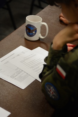 Lt. Kedra Agnieszka, Polish Air Force ground control intercept weapons director, reads through her first “quiz” following a briefing at the 128th Air Control Squadron, Volk Field Air National Guard Base, Wisconsin, June 10, 2015. As part of the State Partnership Program, four service members from Poland spent their time in the United States working beside 128 ACS Airmen. (U.S. Air National Guard photo by Staff Sgt. Andrea F. Rhode)