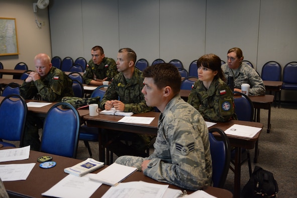Members of the Polish Air Force receive their first briefing prior to entering the operations module at the 128th Air Control Squadron, Volk Field Air National Guard Base, Wisconsin, June 10, 2015. As part of the State Partnership Program, the four service members spent their time in the United States working beside 128 ACS Airmen. (U.S. Air National Guard photo by Staff Sgt. Andrea F. Rhode)