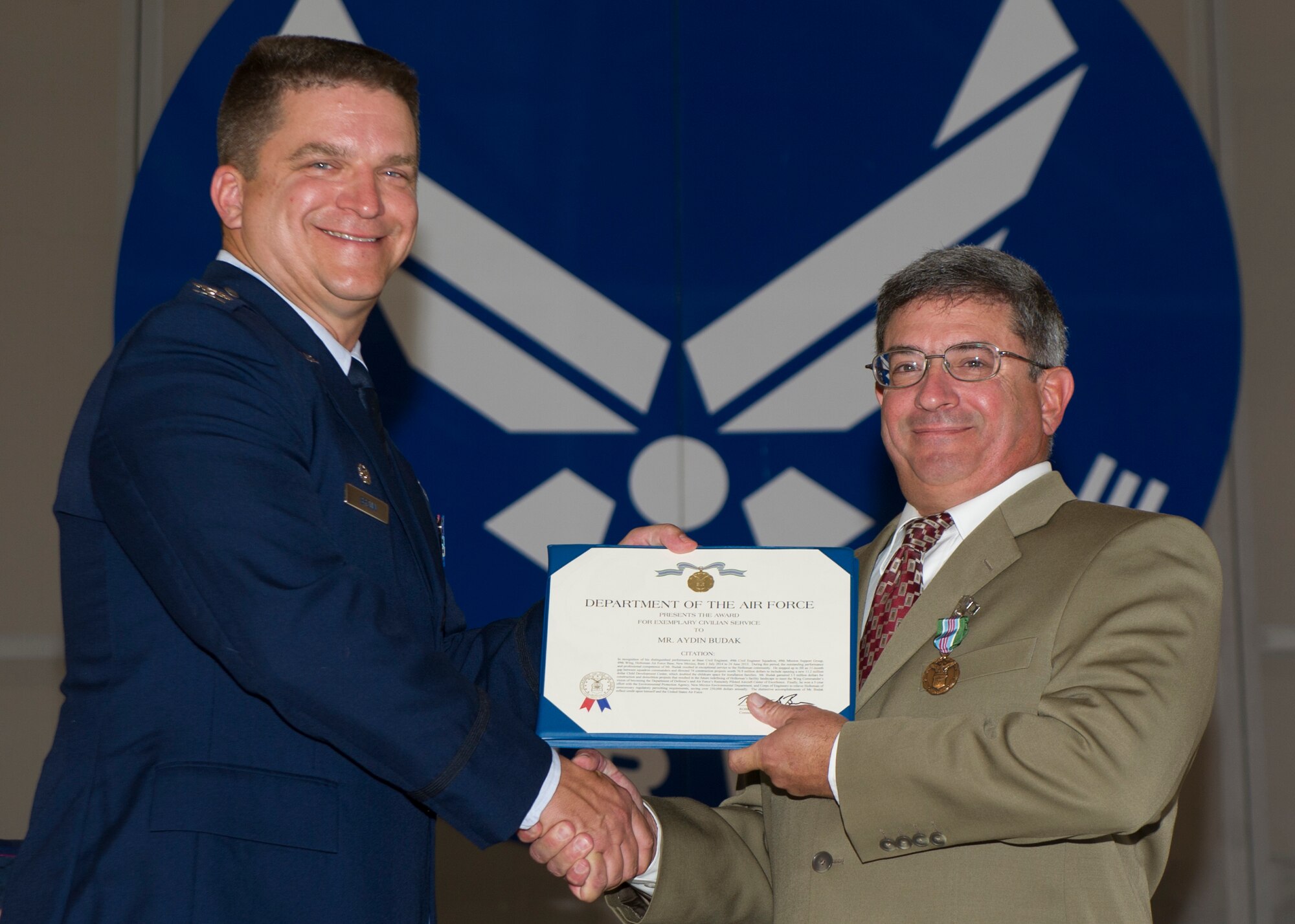 Colonel Greg Brown, 49th Mission Support Group commander, and Aydin Budak, 49th Civil Engineer Squadron acting commander, pose for a photo after Brown presented Budak with The Exemplary Civilian Service award during the 49th CES Assumption of Command at Holloman Air Force Base, N.M., June 25, 2015. Budak received the award for his exceptional performance as the acting commander of the CES. (U.S. Air Force photo by Airman 1st Class Emily A. Kenney/Released) 