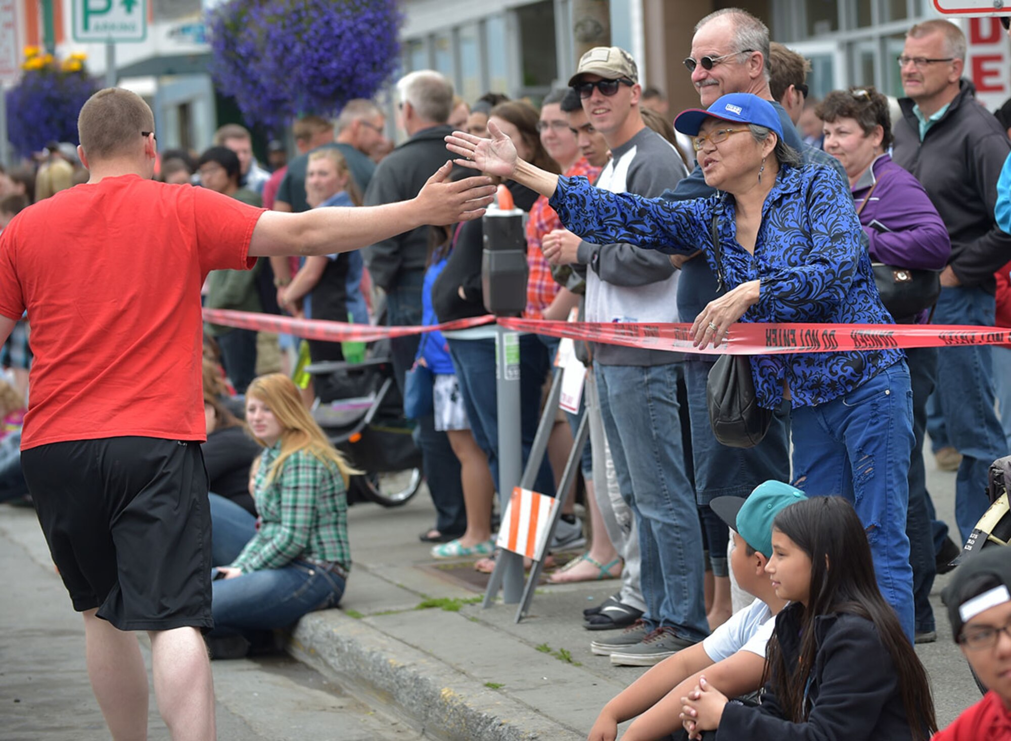 An Airman assigned to the Joint Base Elmendorf-Richardson fire department reaches to high-five a spectator during the Hero Games in downtown Anchorage, Alaska, during the Solstice Celebration, Saturday, June 20, 2015. The annual competition is hosted by the Anchorage Downtown Partnership, and pits military members and local civilian firefighter teams against each other in various team-based challenges as part of a larger event celebrating the longest day of the year. (U.S. Air Force photo/Justin Connaher)