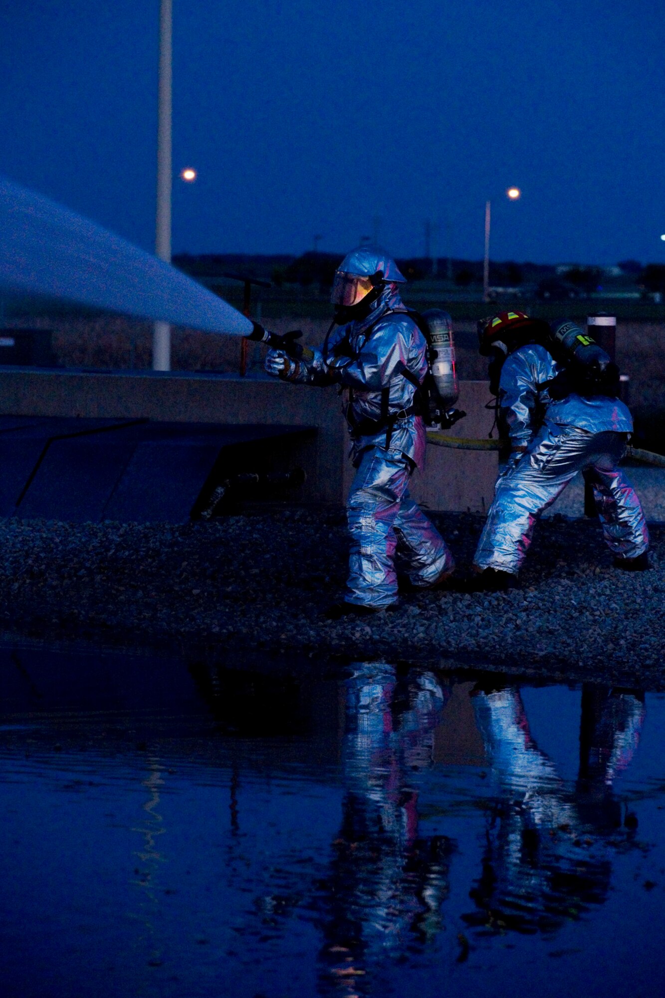 Jason Hofmeister, front, and Capt. Jason Cahill, both Grissom Fire Department firefighters, use a fire hose to exterminate a fire on a mock airframe at Grissom Air Reserve Base, Ind. May 21, 2015. The night-time training exercise allows firefighters to become accustomed to using their equipment in poor-visibility conditions. (U.S. Air Force photo/Tech. Sgt. Benjamin Mota)
