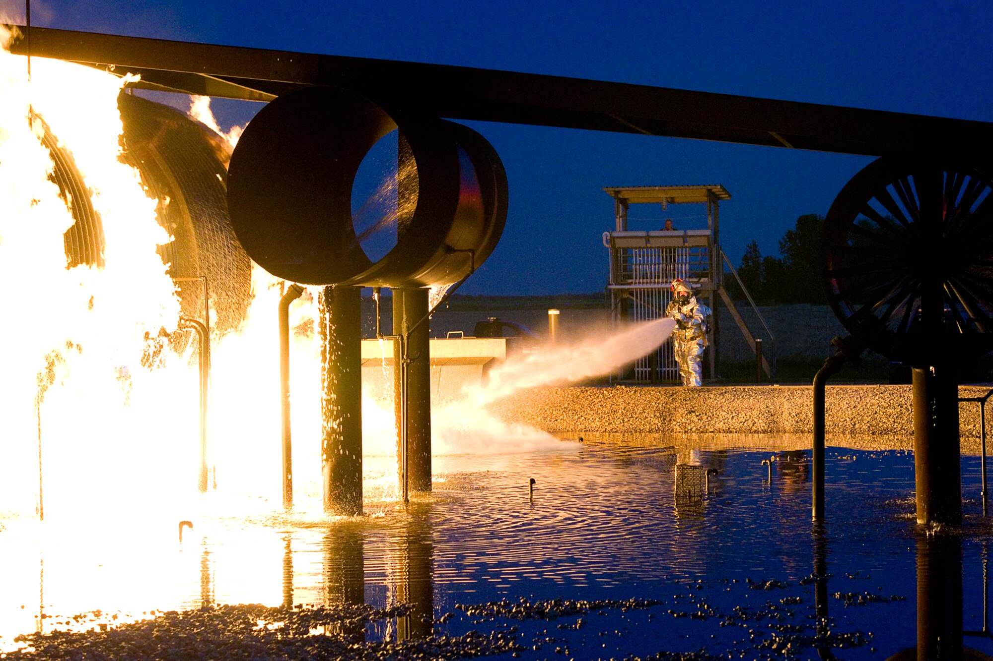 Jason Hofmeister, front, and Capt. Jason Cahill, both Grissom Fire Department firefighters, use a fire hose to exterminate a fire on a mock airframe at Grissom Air Reserve Base, Ind. May 21, 2015. Grissom's fire pit uses propane gas to ignite a mock airframe providing firefighters realistic training. (U.S. Air Force photo/Tech. Sgt. Benjamin Mota)