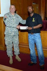 U.S. Army Maj. Bret Gilmore, Regiment Chapel pastoral coordinator, left, hands 1st Sgt. Ernest Evans, Bravo Company, 2nd Battalion, 210th Aviation Regiment, 128th Aviation Brigade first sergeant, a donation at Fort Eustis, Va., June 23, 2015. The donation was given to the Fort Eustis Diamond Council, consisting of post first sergeants, to assist the council with helping Fort Eustis Soldiers. (U.S. Air Force photo by Senior Airman Kimberly Nagle/Released)