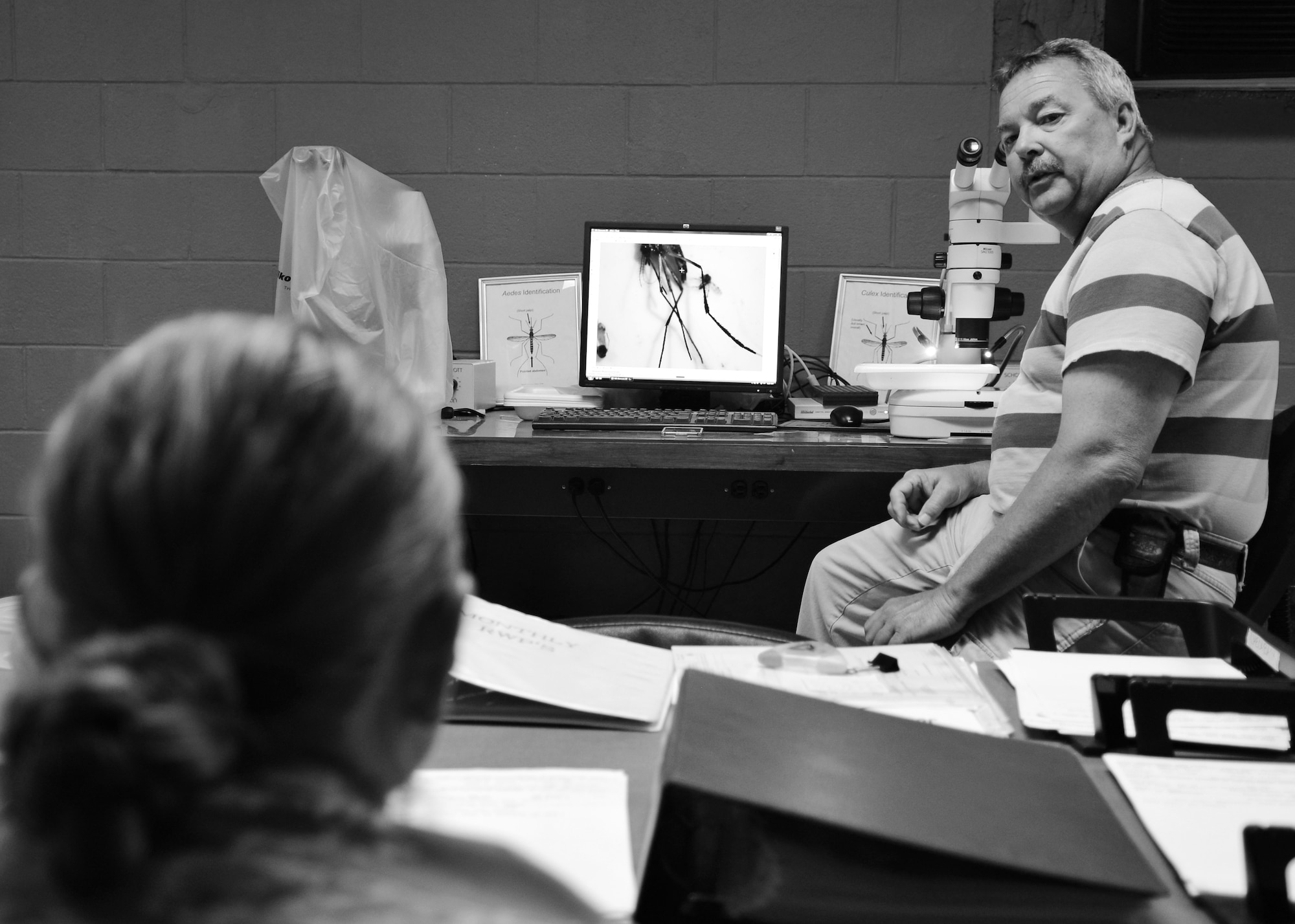 Mitchel Burcham, 633rd Civil Engineering Squadron Pest Management technician, speaks to U.S. Air Force Airman 1st Class Ashley King, 633rd CES Pest Management apprentice, at Langley Air Force Base, Va., June 18, 2015. Burcham trains the Pest Management Airmen on how to identify different mosquitos so they can measure each species’ population. (U.S. Air Force photo by Airman 1st Class Devin S. Michaels/Released)