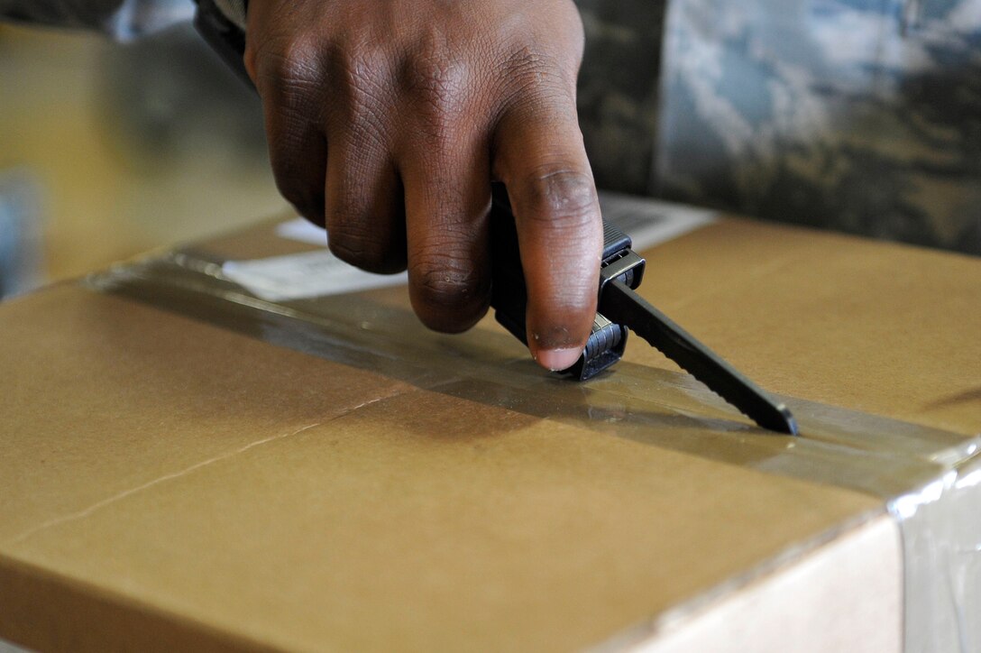 U.S. Air Force Senior Airman Anthony Castello, 633rd Logistics Readiness Squadron Traffic Management Operations inbound and receiving technician, opens a box at Langley Air Force Base, Va., June 24, 2015. After opens the shipments, technicians place receiving documents and stock labels to ensure proper delivery. (U.S. Air Force photo by Senior Airman Breonna Veal) 