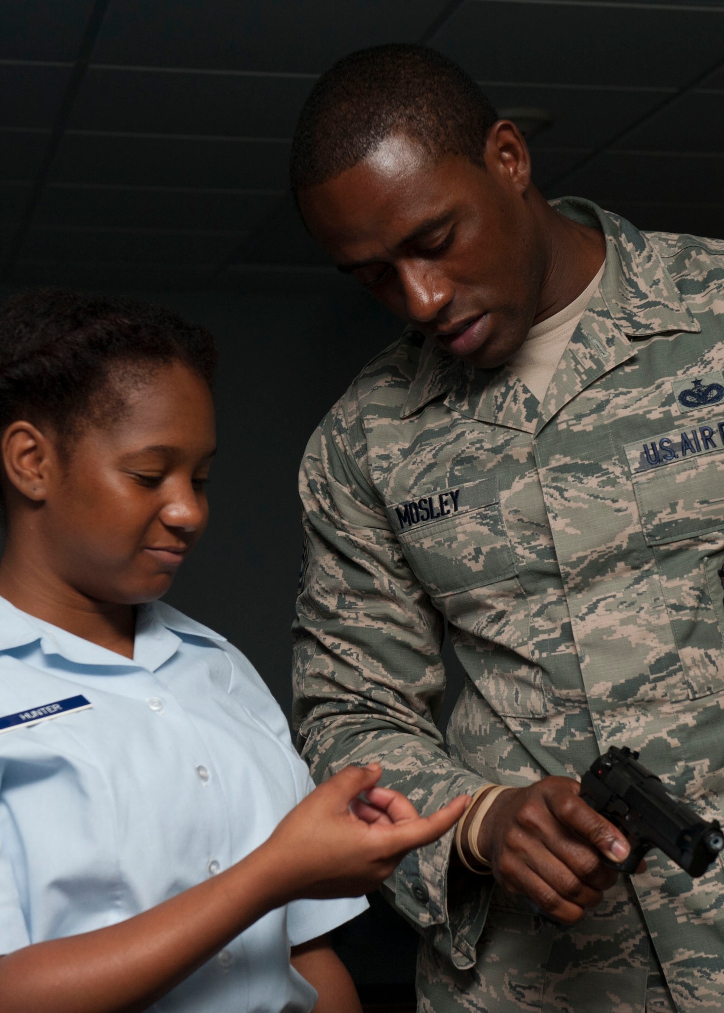 U.S. Air Force Tech. Sgt. Franklin Mosley, 633rd Security Forces Squadron trainer, demonstrates proper hand placement on the virtual range simulator’s M-9 pistol to Deshenell Hunter, Lakeland High School Junior ROTC cadet during Shadow Day at Langley Air Force Base, Va., June 23, 2015. The cadets were able to participate in security forces’ team scenarios using the virtual range simulator. (U.S Air Force photo by Staff Sgt. John D. Strong II/ Released)