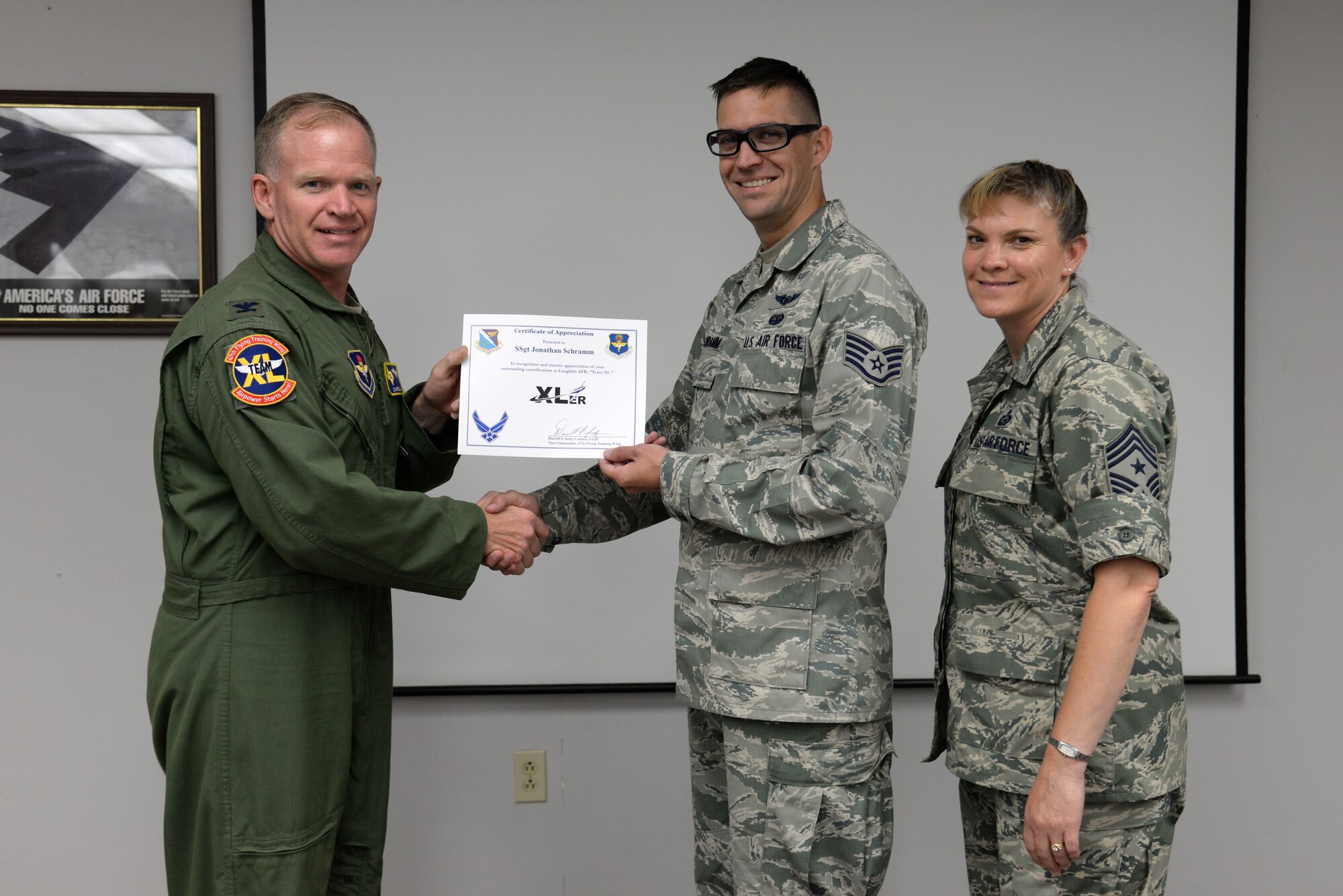 Staff Sgt. Jonathan Schramm, center, 47th Communications Squadron cyber operations journeyman, poses with Col. Darrell Judy, 47th Flying Training Wing vice commander, and Chief Master Sgt. Teresa Clapper, 47th FTW command chief, after accepting the XLer of the Week award, here, June 24, 2015. The XLer is a weekly award chosen by wing leadership and is presented to those who consistently make outstanding contributions to their unit and Laughlin. (U.S. Air Force photo by Airman 1st Class Brandon May)