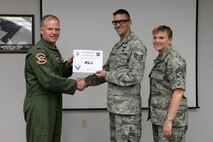 Staff Sgt. Jonathan Schramm, center, 47th Communications Squadron cyber operations journeyman, poses with Col. Darrell Judy, 47th Flying Training Wing vice commander, and Chief Master Sgt. Teresa Clapper, 47th FTW command chief, after accepting the XLer of the Week award, here, June 24, 2015. The XLer is a weekly award chosen by wing leadership and is presented to those who consistently make outstanding contributions to their unit and Laughlin. (U.S. Air Force photo by Airman 1st Class Brandon May)