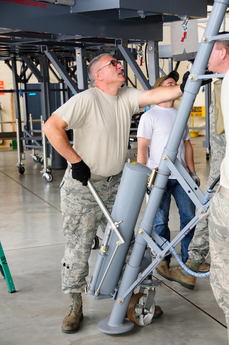 U.S. Air Force Master Sgt. Kevin Mignosa, 145th Maintenance Squadron, ISO Dock leader, maneuvers a wing jack into place as other maintainers install new Isochronal Inspection (ISO) Aircraft Maintenance Platforms around a 145th Airlift Wing, C-130 Hercules aircraft at the North Carolina Air National Guard base, Charlotte Douglas International Airport, June 2, 2015. (U.S. Air National Guard photo by Master Sgt. Patricia F. Moran, 145th Public Affairs/Released)