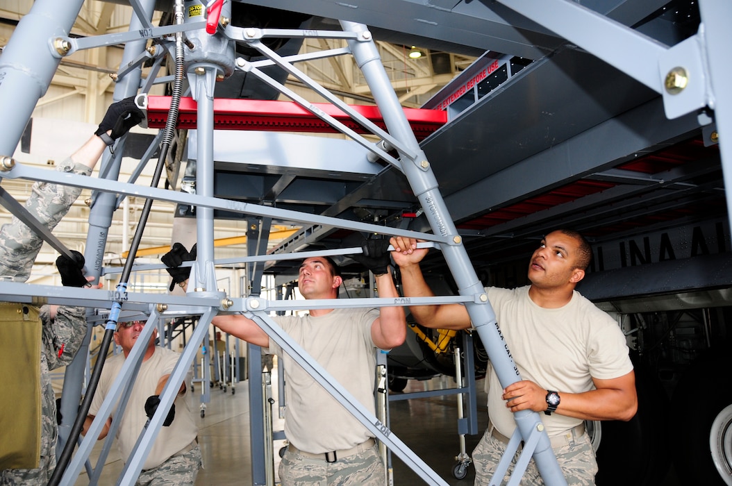 U.S. Air Force Master Sgt. Kevin Mignosa, 145th Maintenance Squadron, ISO Dock leader, Senior Airman Jonathan Yerkes and Kevin Hubbard, 145th aircraft maintainers, maneuver a wing jack into place during installation of new Isochronal Inspection (ISO) Aircraft Maintenance Platforms at the North Carolina Air National Guard base, Charlotte Douglas International Airport, June 2, 2015. (U.S. Air National Guard photo by Master Sgt. Patricia F. Moran, 145th Public Affairs/Released)