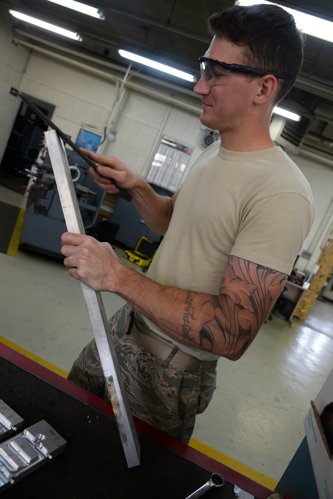 Senior Airman Justin Weeks, 374th Maintenance Squadron aircraft metals technology journeyman, smoothens the edge of a metal piece in the fabrication shop at Yokota Air Base, Japan, June 23, 2015. The shop often receives C-130 Hercules exhaust pipes to repair utilizing the technicians’ grinding and welding skills. (U.S. Air Force photo by Senior Airman David Owsianka/Released)
