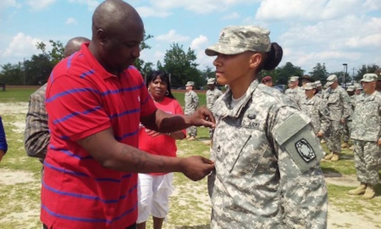 Army Staff Sgt. Janina Simmons, right, a Patriot launching station enhanced operator with 69th Air Defense Artillery Brigade, receives her drill sergeant badge from her mentor, Army Sgt. 1st Class Yancy Hampton, the first sergeant of Bravo Battery, 1st Battalion, 44th Air Defense Artillery Regiment, during a ceremony at Fort Jackson, S.C., June 9, 2015. Simmons defies negative stereotypes regarding both gays and women serving in the military through her top-notch performance record. Courtesy photo