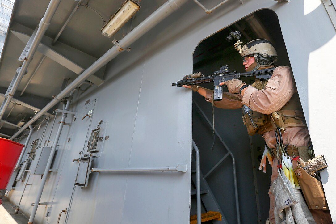A U.S. Marine watches around a corner during visit, board, search and seizure training aboard the USNS Robert E. Peary in the Atlantic Ocean, June 19, 2015.