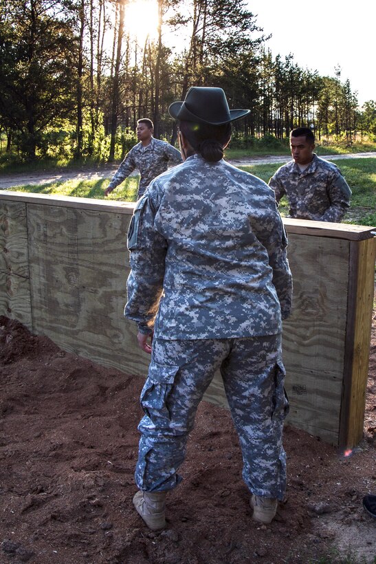 Army Reserve Sgt. 1st Class Lourdes Navarro, foreground, observes as soldiers take on the low-wall obstacle at the confidence course on Fort McCoy, Wis., June 19, 2015.
