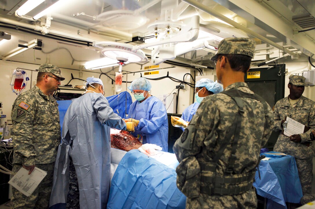 Navy and Army reservists perform a simulated surgery on a patient wearing an anatomically correct "cut suit" suit designed for surgical practice during Global Medic at Fort McCoy, Wis., June 14, 2015.