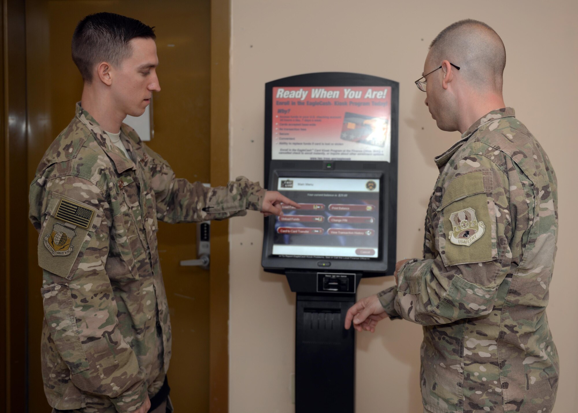 U.S. Air Force Senior Airman Corey Gibson, 455th Air Expeditionary Wing Finance Management customer service technician, assists a customer at an eagle cash card machine, June 24, 2015, at Bagram Airfield, Afghanistan. Gibson is the only finance customer service technician in Afghanistan and ensures all Bagram Active Duty, Reserve and Guard Airmen as well as U.S. civilian members are financially set during their deployment here. (U.S. Air Force photo by Senior Airman Corey Gibson/Released)
