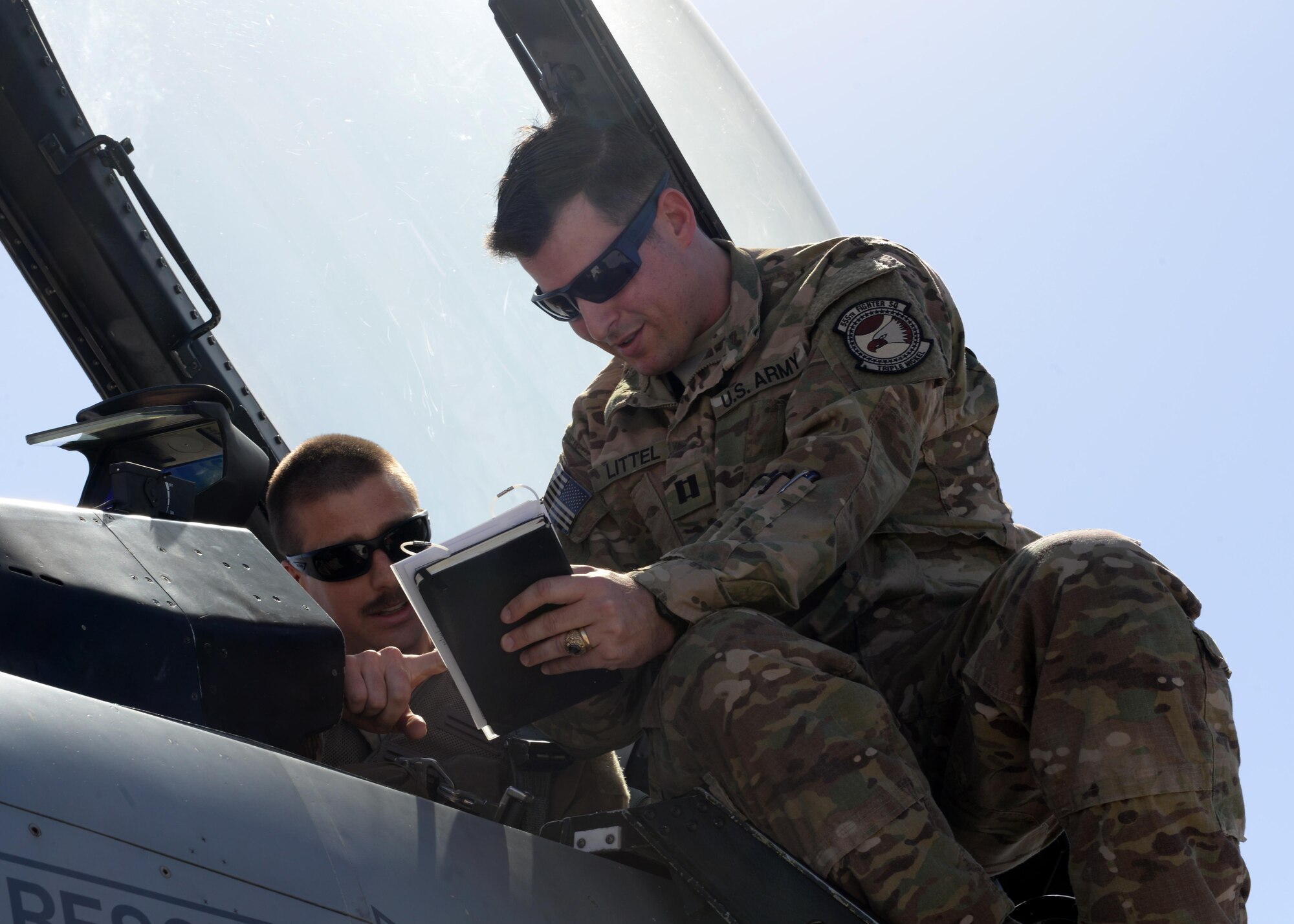 U.S. Army Capt Andrew Littel, 555th Expeditionary Fighter Squadron ground liaison officer, reviews information with a pilot before takeoff June 12, 2015, at Bagram Airfield, Afghanistan. As a GLO, Littel briefs pilots on mission parameters as well as provides pilots with a good perspective of what guys on the ground are going through. (U.S. Air Force photo by Senior Airman Cierra Presentado/Released)    