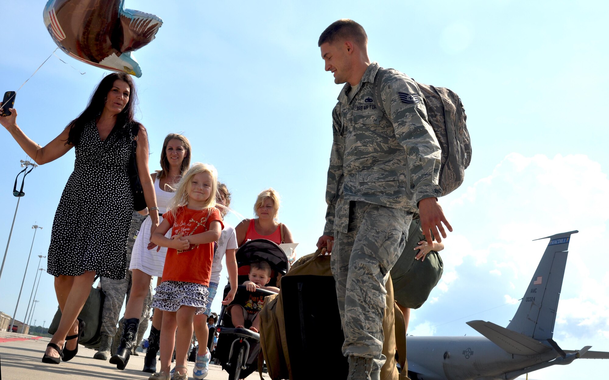 Tech. Sgt. Clayton King makes leaves the flightline with his family after returning from an extended deployment to southwest Asia June 17, 2015 at MacDill Air Force Base. While deployed, members of the 927th Air Refueling Wing supported Operation Inherent Resolve by extending global reach while providing global air refueling and airlift operations. (U.S. Air Force photo by Staff Sgt. Adam C. Borgman)