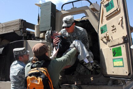 Staff Sgt. Kerry Whitaker, chief of the M270A1 launcher from 2-18 FAR, helps Honorary Soldier Erick Morales into an M270A1 Launcher to do his ride and process a simulated fire mission. Whitney Marsh, the respite care provider for Erik, contacted the National Guard to help make Erik's wish of being a Soldier come true.