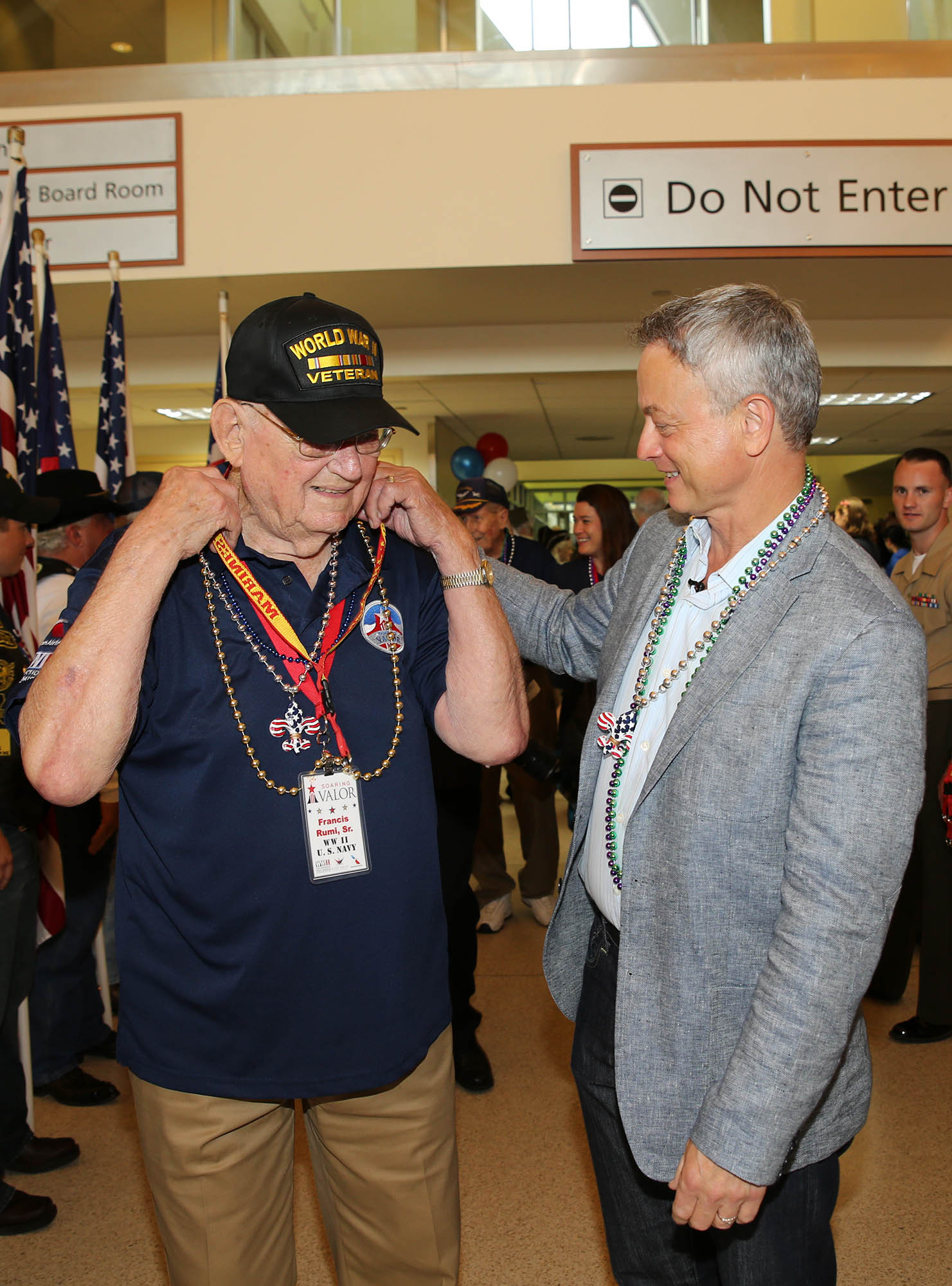 Academy nominated actor Gary Sinise helps Francis Rumi, Sr., a World War II Navy veteran, place beads and a Marine Corps lanyard around his neck during the welcome ceremony held in honor of approximately 40 other veterans of the "Greatest Generation" at the Louis Armstrong International Airport in New Orleans, June 25, 2015. Sinise and volunteers from the Gary Sinise Foundation organized a special trip for the veterans to visit the National World War II Museum in downtown New Orleans later that day.  