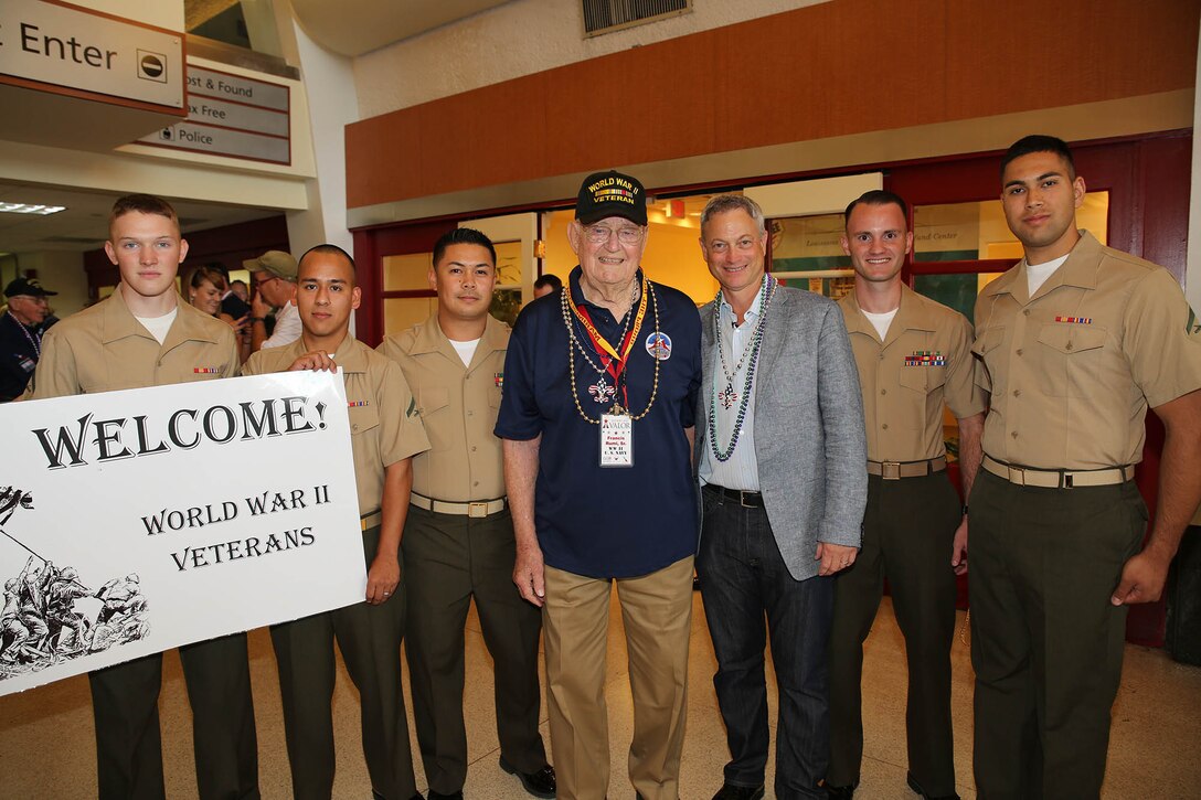 World War II veteran Francis Rumi, Sr. and actor Gary Sinise (center) share a moment with Marines from Marine Forces Reserve during the welcome ceremony at the Louis Armstrong International Airport in New Orleans, June 24, 2015.  Sinise, along with volunteers from the Gary Sinise Foundation, travelled to New Orleans with nearly 50 veterans of World War II to escort them to the National World War II Museum as part of the foundation's program to honor those who have fought to protect America's freedoms. 