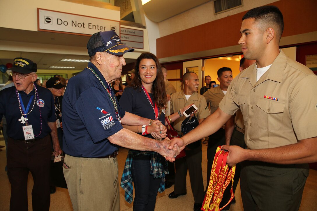 Lance Cpl. Alan Rodriguez, fiscal clerk with Headquarters Battalion, Marine Forces Reserve, welcomes a WWII veteran as he arrives to the Louis Armstrong Airport in New Orleans, June 24, 2015.  Rodriguez, along with other Marines from MARFORRES, and other service members and volunteers, participated in the welcome ceremony organized by the Gary Sinise Foundation. The veterans flew to New Orleans to visit the WWII Museum in downtown New Orleans.