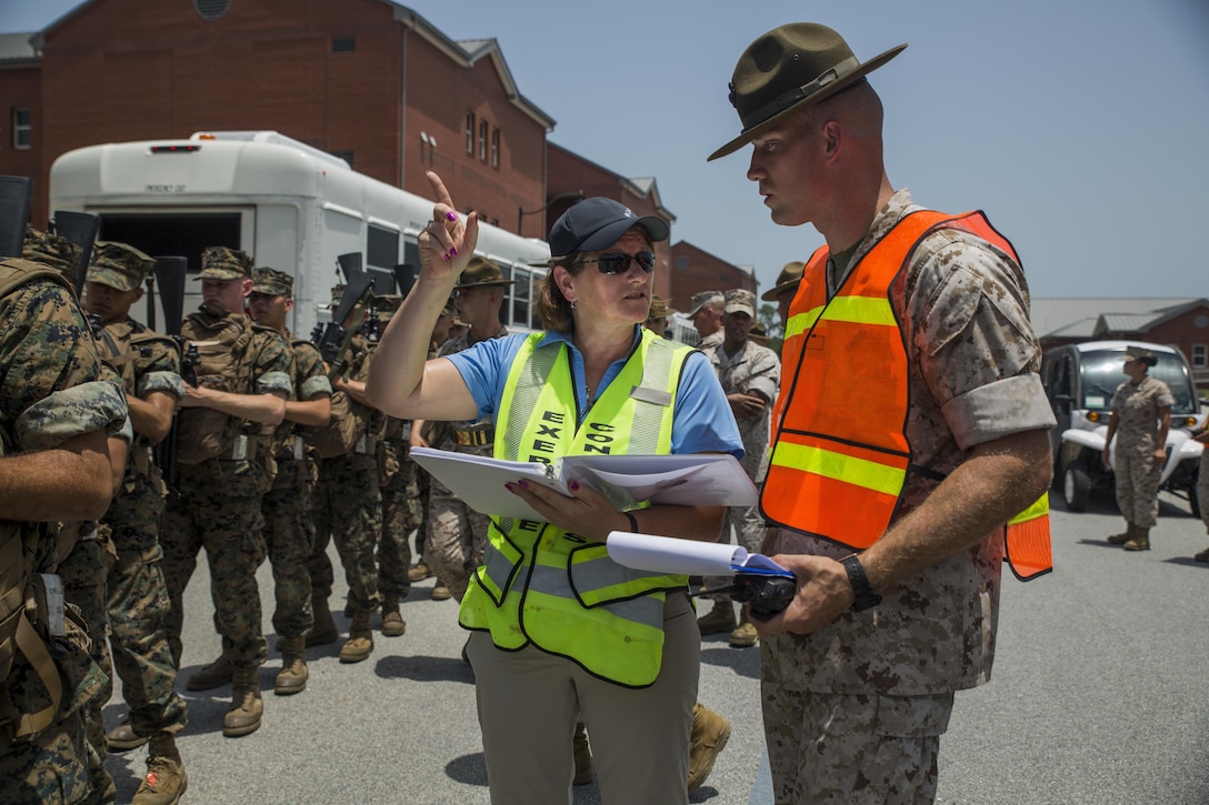 Mary B. Skarote, an exercise planner for the 2015 Parris Island hurricane exercise, discusses evacuation procedures with a Lima Company, 3rd Recruit Training Battalion, drill instructor June 24, 2015, on Parris Island, S.C. The practiced evacuation was part of a hurricane exercise that simulated the efforts needed to evacuate permanent personnel, recruits and equipment. After the week-long exercise, officials will review the outcome and apply any necessary changes to ensure MCRD Parris Island can continue making Marines regardless of what mother nature throws at the Lowcountry.