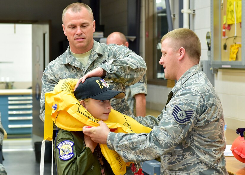 Master Sgt. Don McCormick and Tech Sgt. Ed Peggs, both with the 910th Airlift Wing’s aircrew life support equipment show, help Ethan Hoffman remove a life vest here, June 24, 2015. Twelve-year-old Ethan was sworn in as an honorary second lieutenant as he became the 910th Airlift Wing’s 62nd Pilot for a Day, receiving a day of military experiences and mementos. Ethan was selected for the program by Akron Children’s Hospital in Boardman where he is treated for Bartter Syndrome, a rare kidney disease he has had since birth. (U.S. Air Force photo/Eric M. White)