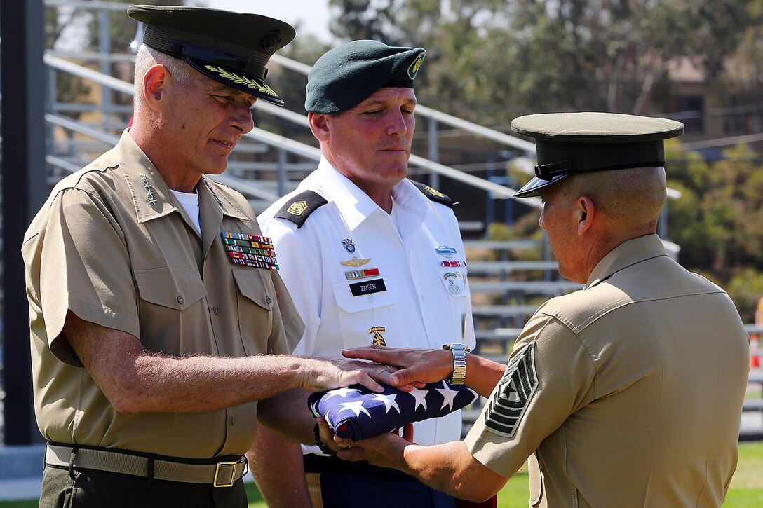 Gen. John F. Kelly, left, and Command Sgt. Maj. William B. Zaiser presented Sgt. Maj. Juan M. Hidalgo Jr. with a flag during Hidalgo’s retirement ceremony at the 11 Area Parade Field, June 26. Kelly is the commander of the U.S. Southern Command and Zaiser is the command senior enlisted advisor to U.S. Southern Command. (Photo by Lance Cpl. Asia J. Sorenson/Released)