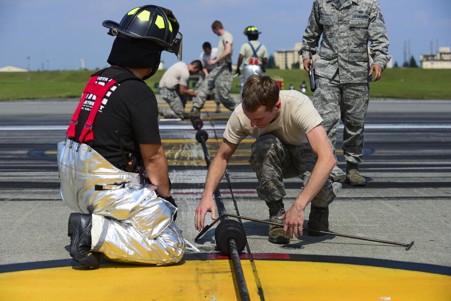 U.S. Air Force Airmen from the 374th Civil Engineer Squaron ensure the aircraft arresting system is properly in place at Yokota Air Base, Japan, June 24, 2015. The AAS is inspected every day by the power production shop and fire department personnel. (U.S. Air Force photo by Senior Airman David Owsianka/Released)