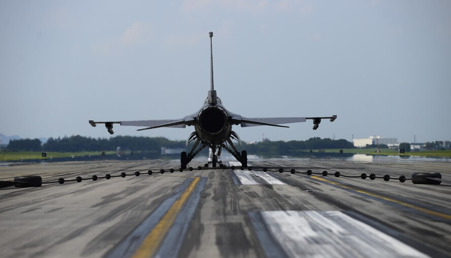 A U.S. Air Force F-16 Fighting Falcon from Misawa Air Base, Japan, slows down on the runway at Yokota Air Base, Japan, June 24, 2015. As the reel of the aircraft arresting system spins it activates a hydraulic pump which compresses a brake pad to safely slow the aircraft. The aircraft can go from a speed of 180 knots to a complete hault in approximately 10 seconds. (U.S. Air Force photo by Senior Airman David Owsianka/Released)