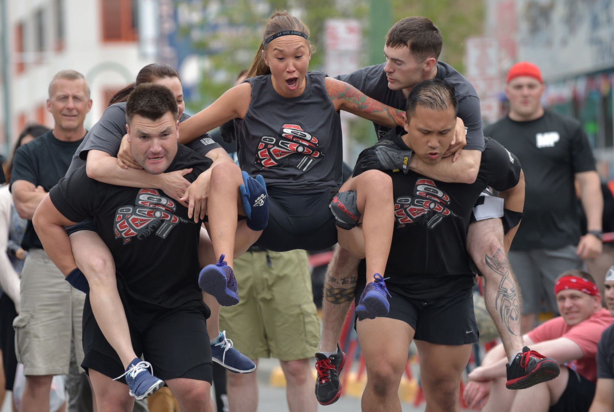 U.S. Army Spc. Allison Booshu, Medical Detatchment, Alaska Army National Guard, yells as her buddy-carry team races during the Hero Games in downtown Anchorage, Alaska, during the Solstice Celebration, June 20, 2015. The annual competition is hosted by the Anchorage Downtown Partnership, and pits military members and local civilian firefighter teams against each other in various team-based challenges as part of a larger event celebrating the longest day of the year. (U.S. Air Force photo by Justin Connaher/Released)