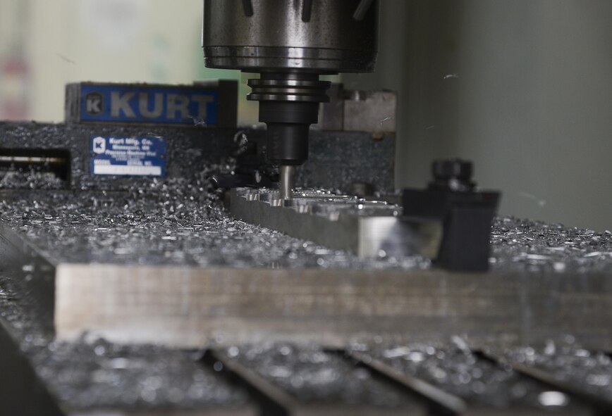 A computer numeric controller router creates a C-130 Hercules crew door arm clamp in the fabrication shop at Yokota Air Base, Japan, June 23, 2015. A CNC router is a computer controlled cutting machine related to the hand held router used for cutting various hard metals, such as wood composites, aluminium, steel, plastics and foams. (U.S. Air Force photo by Senior Airman David Owsianka/Released)