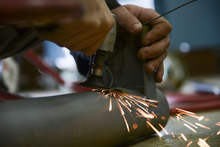 U.S. Air Force Airman 1st Class Curtis Doherty, 374th Maintenance Squadron aircraft metals technology journeyman, sands down part of a tow bar at the fabrication shop at Yokota Air Base, Japan, June 23, 2015. The shop often receives C-130 Hercules exhaust pipes to repair utilizing the technicians' grinding and welding skills. (U.S. Air Force photo by Senior Airman David Owsianka/Released)
