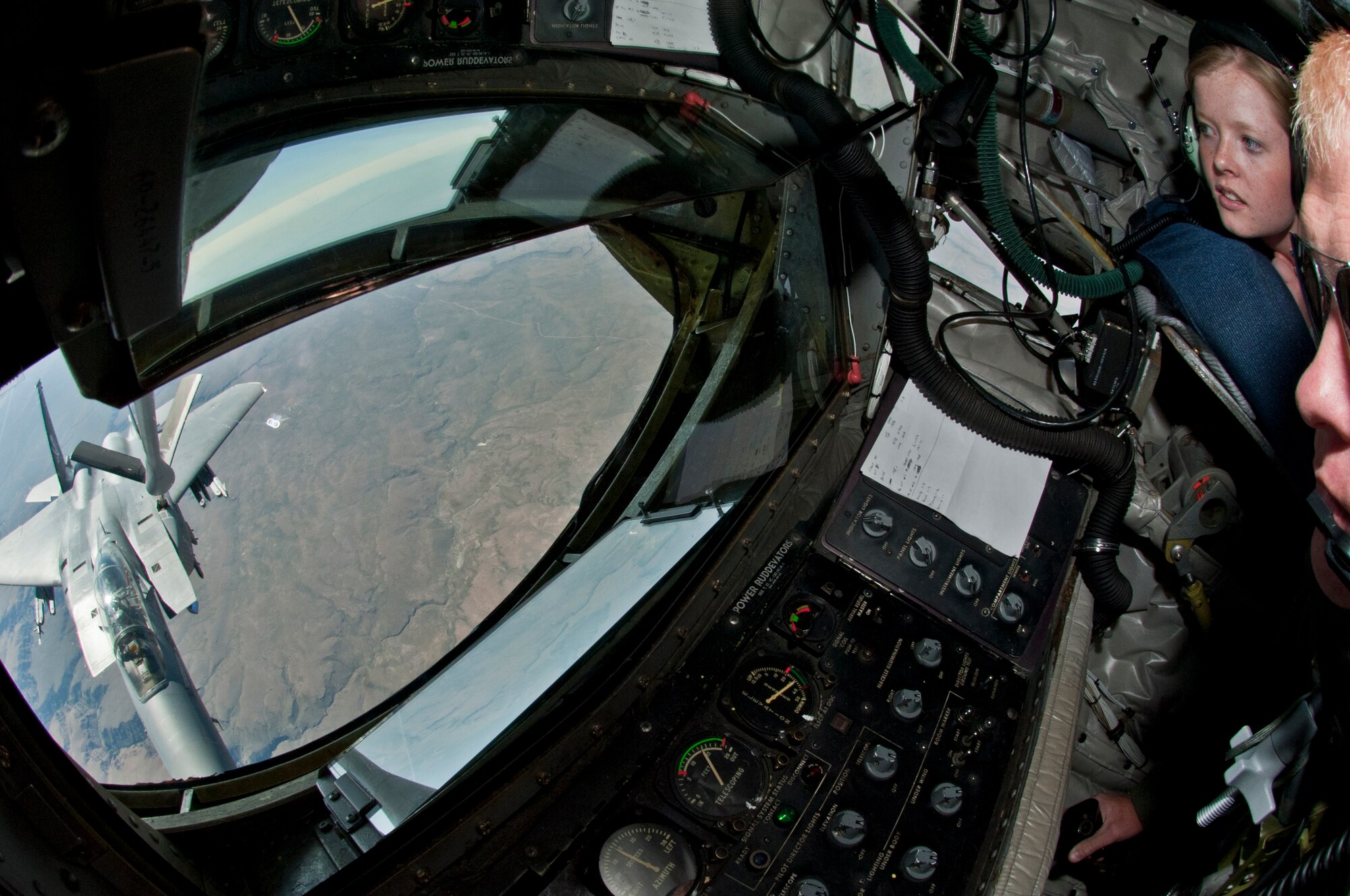 Mandy Welham, Lilac Princess, looks on as Staff Sgt. Jason Markham, 93rd Air Refueling Squadron boom operator, operates the boom pod aboard a KC-135 Stratotanker to refuel an F-15E Strike Eagle June 25, 2015, over the Inland Northwest. The Lilac Princesses Royal Court members were aboard the aircraft as part of an orientation flight. (U.S. Air Force photo/Staff Sgt. Veronica Montes)