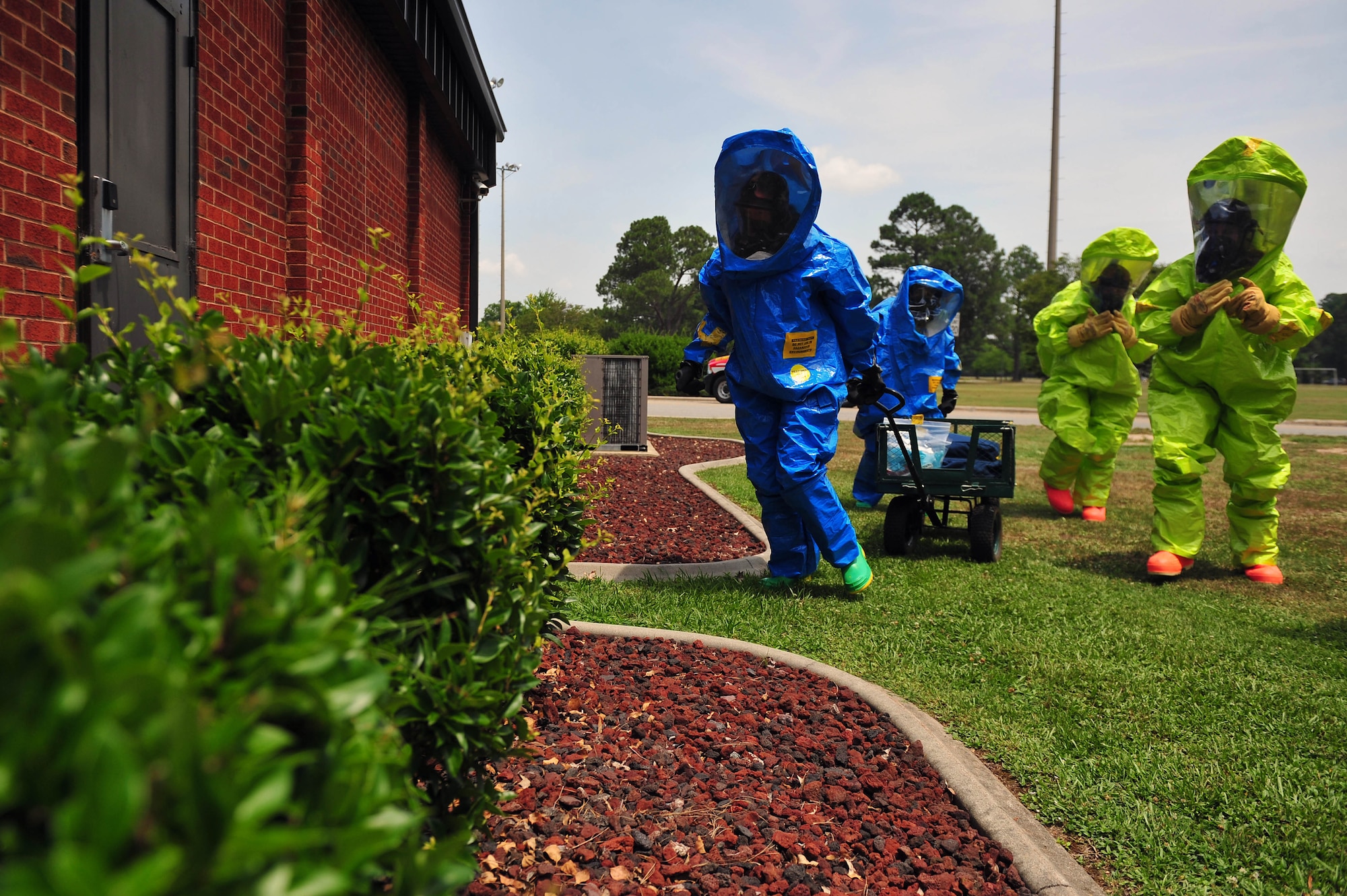 Airmen from the 4th Civil Engineer Squadron emergency management flight and 4th Aerospace Medicine Squadron bioenvironmental flight scout the perimeter of a building during an integrated base emergency response capabilities training exercise, June 24, 2015, at Seymour Johnson Air Force Base, North Carolina. The perimeter was scouted before entry to ensure no simulated hazardous substances were in the area. (U.S. Air Force photo/Senior Airman John Nieves Camacho)