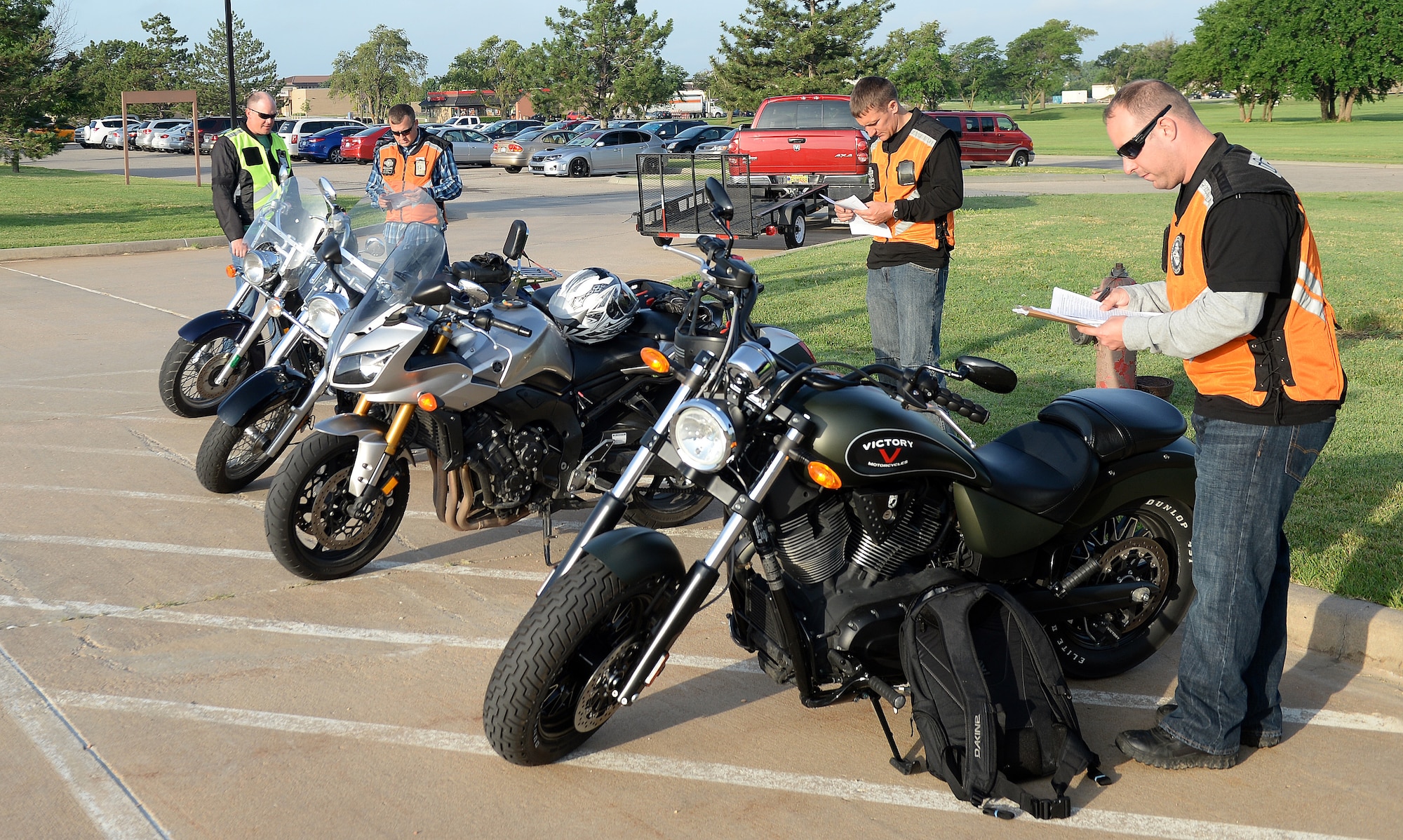 Members of Team McConnell look over their motorcycles using a checklist before taking off for the mentorship ride, June 19, 2015 at McConnell Air Force Base, Kan. The mentorship ride was to recertify riders who have already taken the advanced riders course. (U.S. Air Force photo by Senior Airman Colby L. Hardin)