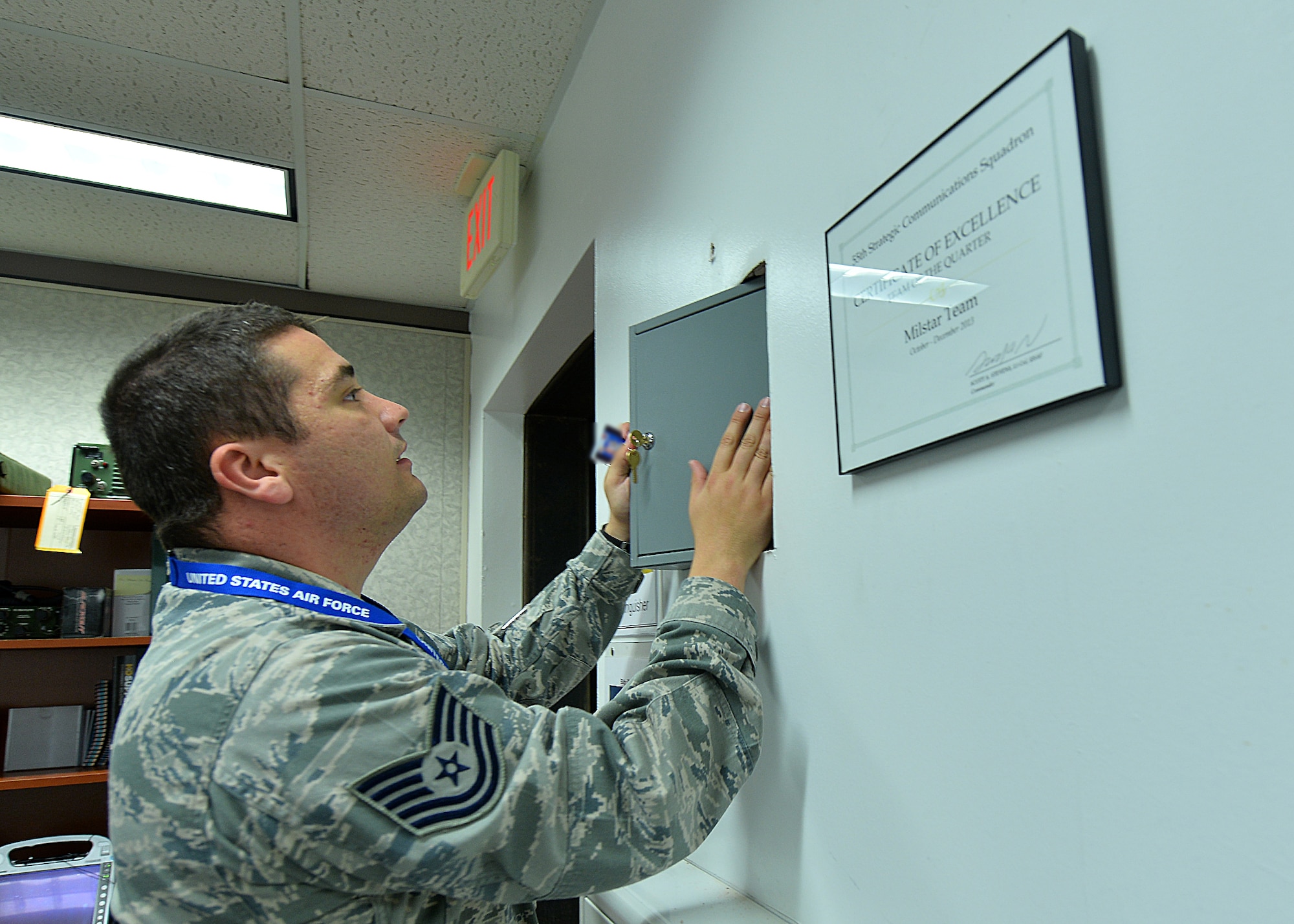 U.S. Air Force Tech. Sgt. Clifford Ferrell, 55th Strategic Communications Squadron, retrieves the MILSTAR time capsule from the wall June 19 at Offutt Air Force Base, Neb. Among the contents of the box were a piece of the ribbon from the ribbon cutting, a MILSTAR training certificate, local newspaper, POW/MIA bracelet, uniform name tapes, fiber optics, chief stripes and several photos. (U.S. Air Force photo by Charles Haymond/Released)