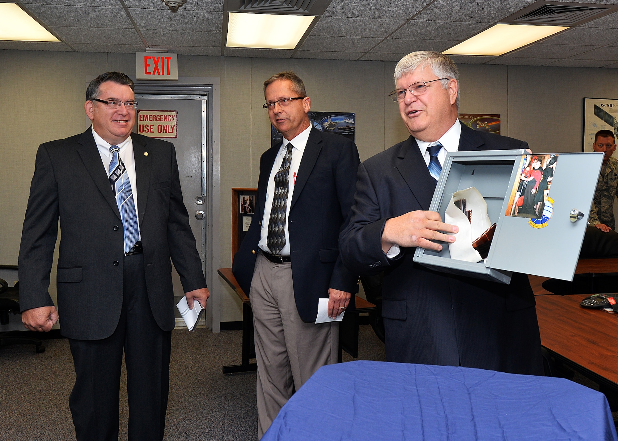 U.S. Air Force Chief Master Sgt. Ret. Bernard Lichvar holds up a time capsule box as U.S. Air Force Master Sgt. Ret. Thomas Reese and Craig Williams look on June 19 during the time capsule unveiling ceremony at Offutt Air Force Base, Neb. The box was planted in the wall of the MILSTAR facility twenty years ago to commemorate its opening. (U.S. Air Force photo by Charles Haymond/Released)