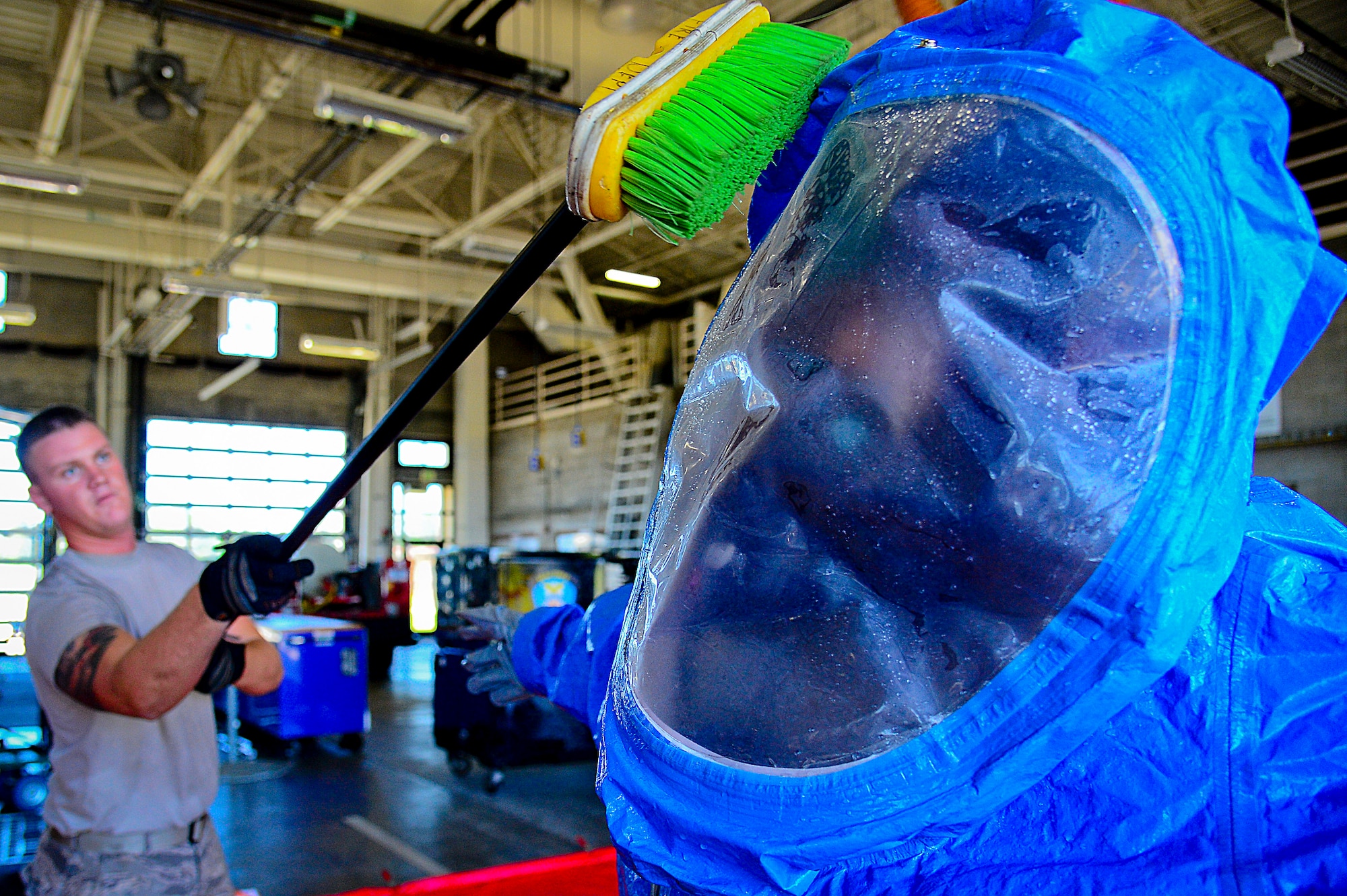 A 6th Civil Engineering Squadron fire fighter scrubs an Airmen in a Level A hazardous material suit during a joint responder training at MacDill Air Force Base, Fla., June 24, 2015. The HAZMAT decontamination line ensures that all personnel leaving the hazardous material “hot zone” are properly cleaned of any and all contaminants. (U.S. Air Force photo by Senior Airman Ned T. Johnston/Released)