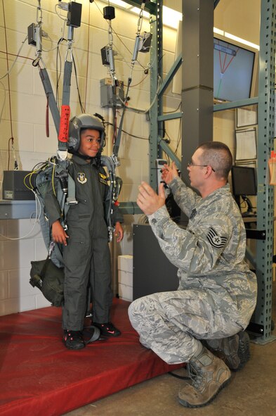 Technical Sgt. Christopher Heaney, aircrew flight equipment technician with the 911th Operations Support Squadron, instructs honorary 2nd Lt. Trenton Bentley on how to use the parachute reality simulator here, June 24, 2015. Trenton, who was diagnosed with acute lymphoblastic leukemia in December 2014, was nominated by Children’s Hospital of Pittsburgh to be the 911th Airlift Wing’s second ever Pilot for a Day. (U.S. Air Force photo by Senior Airman Marjorie A. Bowlden)