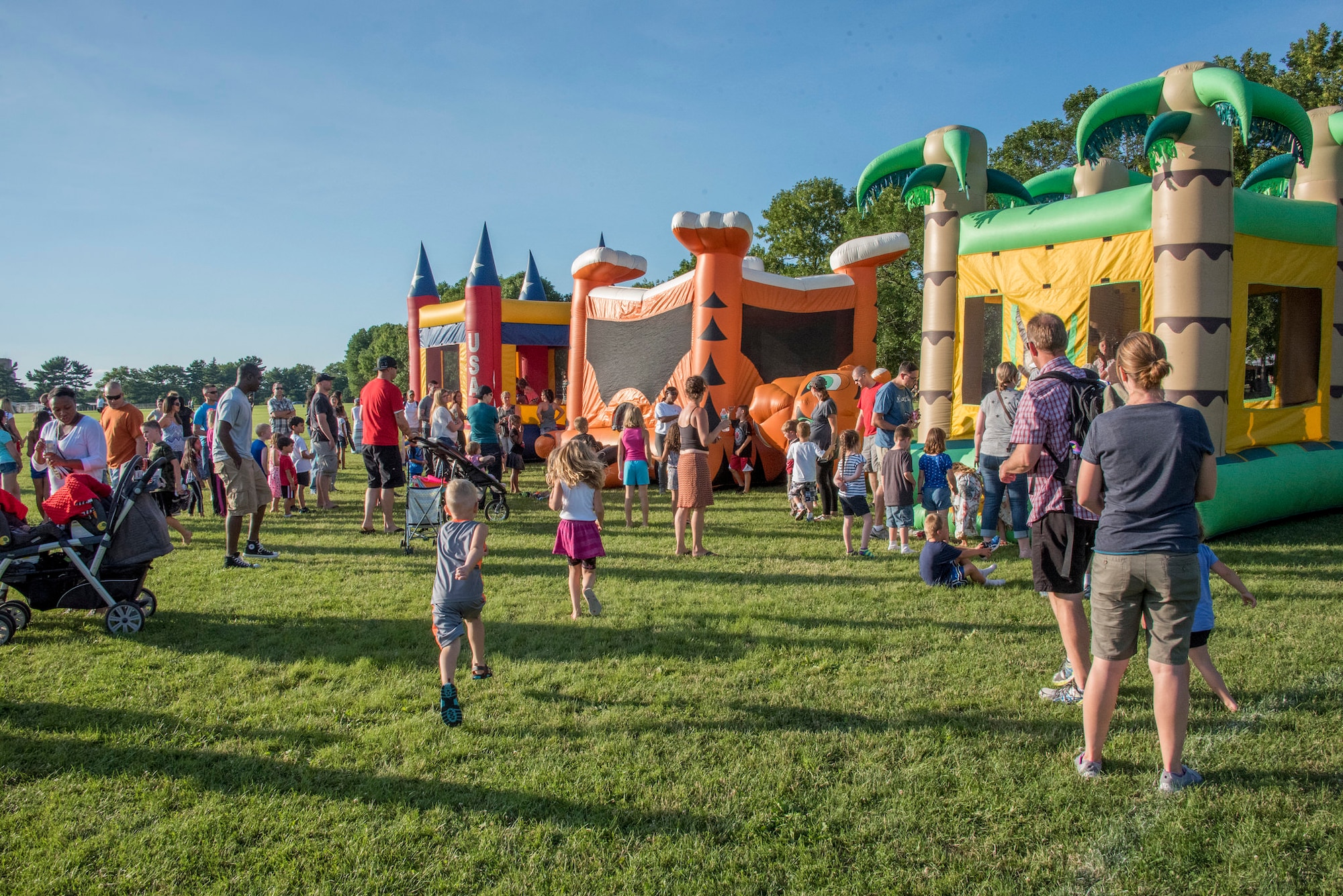 Parents bring children to a play area on Doughboy Field during the Base Backyard Barbecue on Joint Base McGuire-Dix-Lakehurst, N.J., June 24, 2015. The barbecue featured a play area, free food trucks and the Marshall Tucker Band. (U.S. Air Force photo by Senior Airman Tara Williamson/Released)