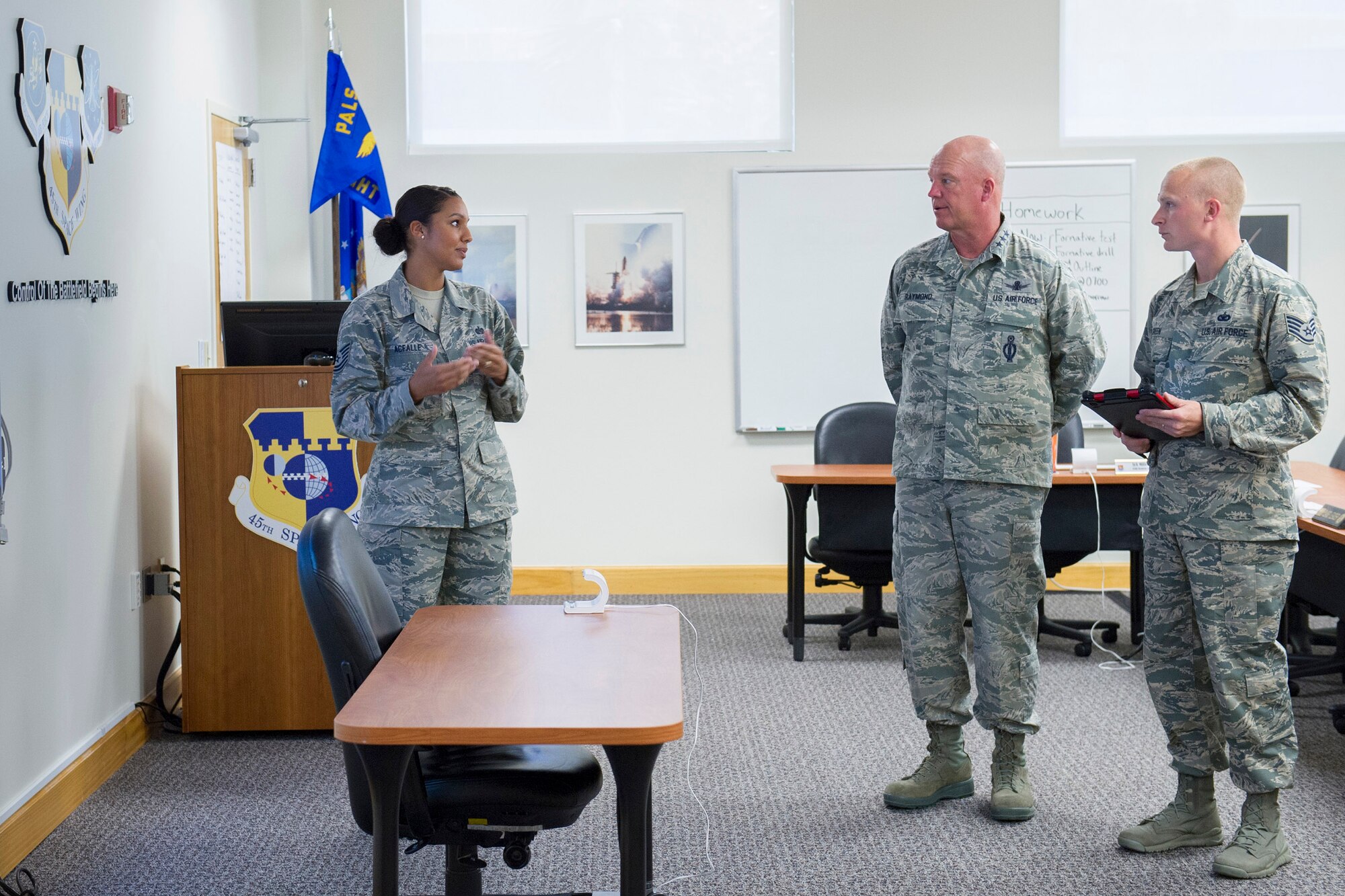 Tech. Sgt. Tamara Acfalle, 45th Force Support Squadron Airman Leadership School instructor, explains what makes the Patrick AFB ALS different from others across the Air Force to Lt. Gen. John Raymond, U.S. Strategic Command's Joint Functional Component Command for Space and 14th Air Force (Air Forces Strategic) commander, while Staff Sgt. Kevin Green, also a 45th FSS ALS instructor, right, holds one of the iPads used for the class. Patrick ALS innovated idea to use iPads exclusively for class content and communication and are the only ones to use them Air Force wide. (U.S. Air Force photo/Matthew Jurgens)(Released)