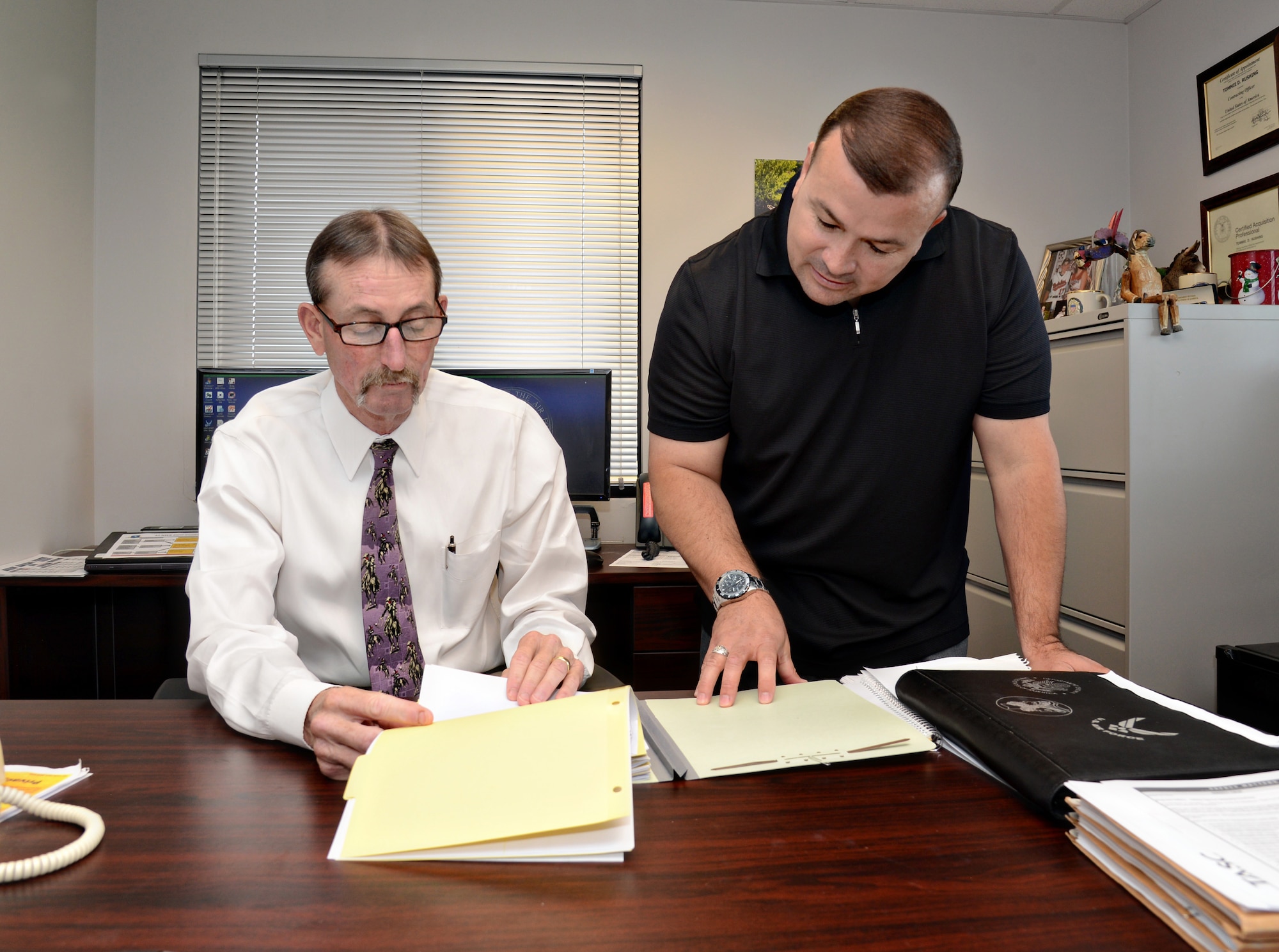 Tommie Rushing, Flight Chief of Cyber Services, and Anthony Owens, a contracting officer, discuss a contract for the 24th Cyberspace Wing. (Air Force photo by Kelly White/Released)

