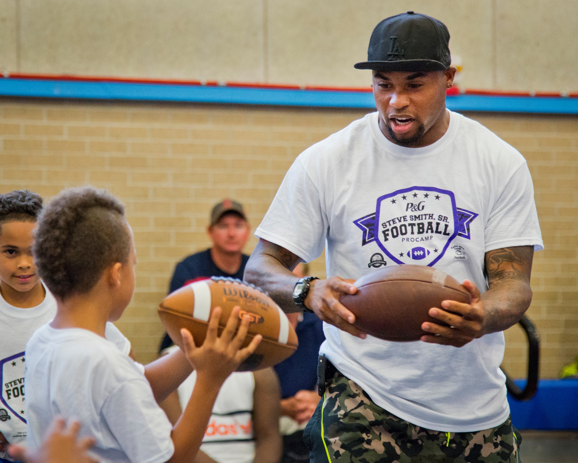 Baltimore Ravens’ wide receiver, Steve Smith, shows a player how to spin the football after a touchdown during the two-day children’s football camp June 24 at Eglin Air Force Base, Fla.  Smith was the professional coach at the camp that taught the kids up-tempo football drills, exercises and scrimmages.  Approximately 150 children attended the camp which was made possible because the Eglin Commissary won a Proctor and Gamble sales contest. (U.S. Air Force photo/Samuel King Jr.)