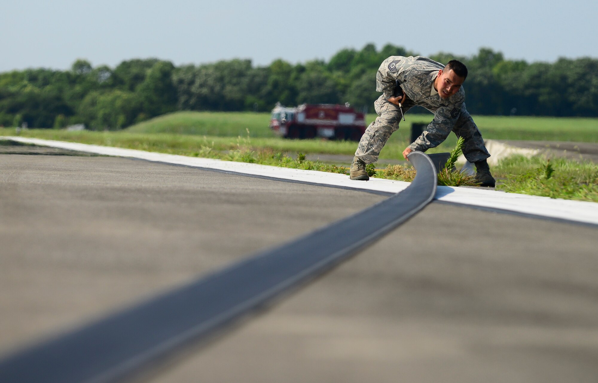 Tech. Sgt. Sonthala Phabmisay, 374th Civil Engineer Squadron electrical power production NCO in charge, checks the nylon tape of the aircraft arresting system for possible damage at Yokota Air Base, Japan, June 24, 2015. The barriers are inspected for torn nylon tapes, cuts in the steel cable, hydraulic leaks or flying debris cause by the engagement of the high-speed aircraft. (U.S. Air Force photo by Senior Airman David Owsianka/Released)